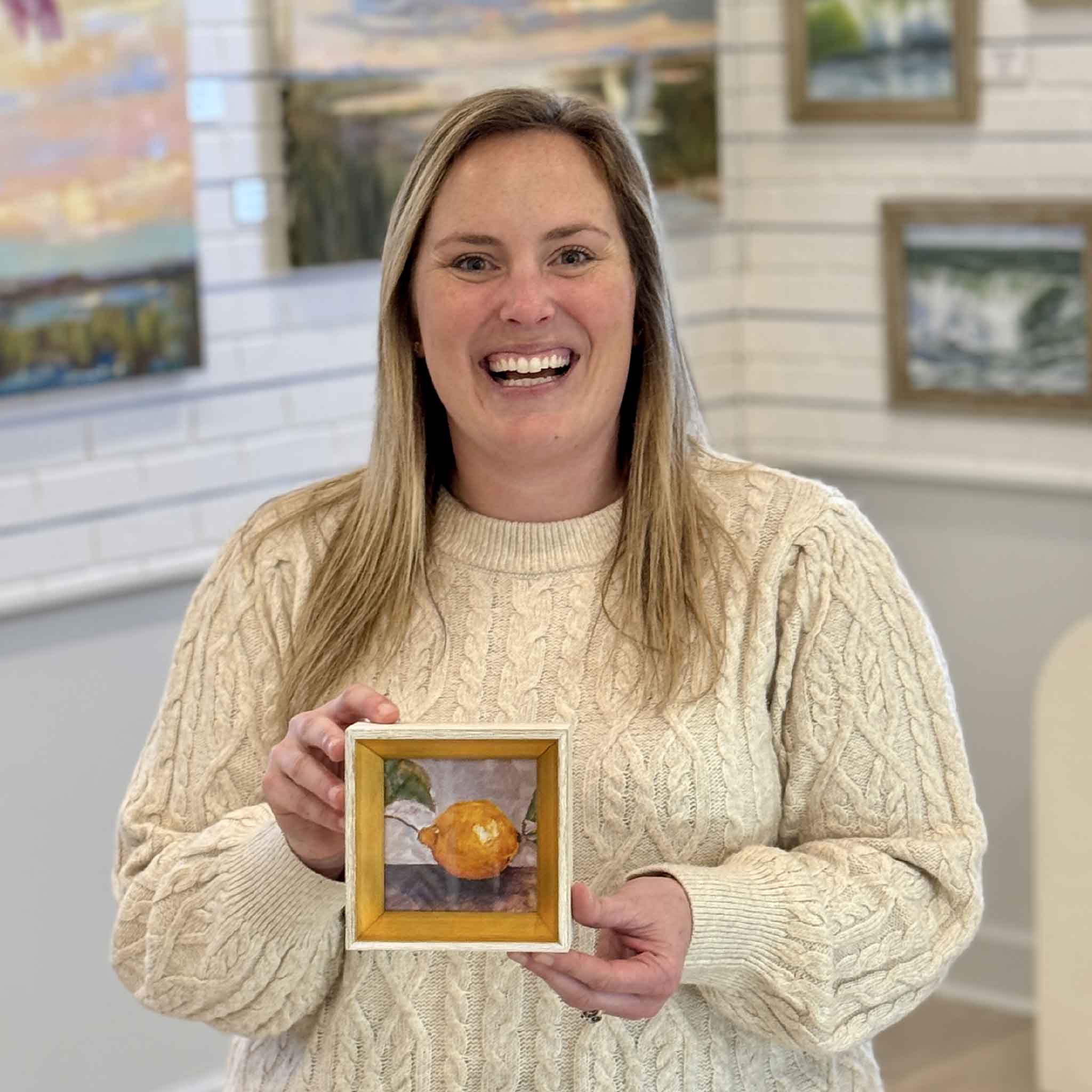 Bordy holding Main Squeeze by local artist Jeanne O’Neal a 4x4 framed lemon fine art print in Jeanne’s signature gold frame at Gray Man Gallery Pawleys Island