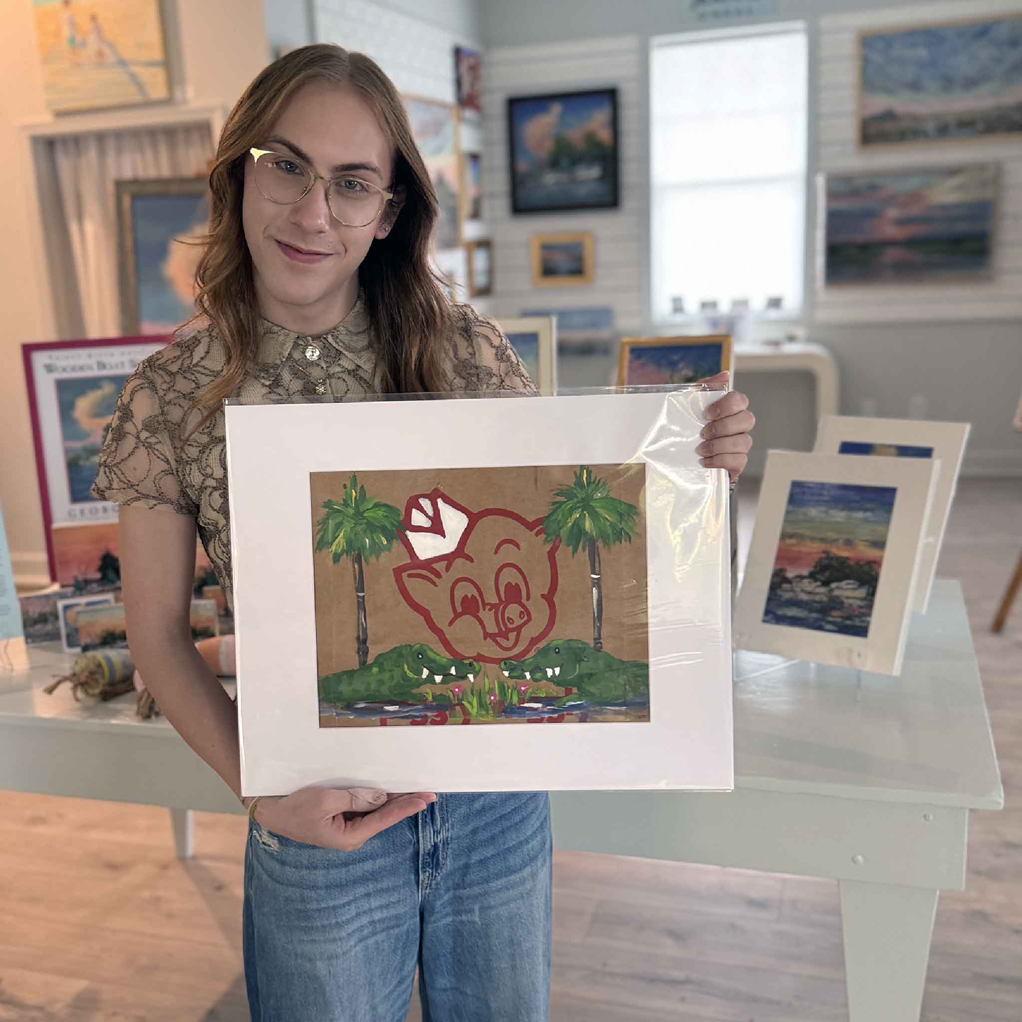 Jenny Reynolds’ “Piggly Wiggly: Gator Blooms” painted on a recycled Piggly Wiggly grocery bag, held inside Gray Man Gallery, featuring gators, blooms, and the iconic pig logo.