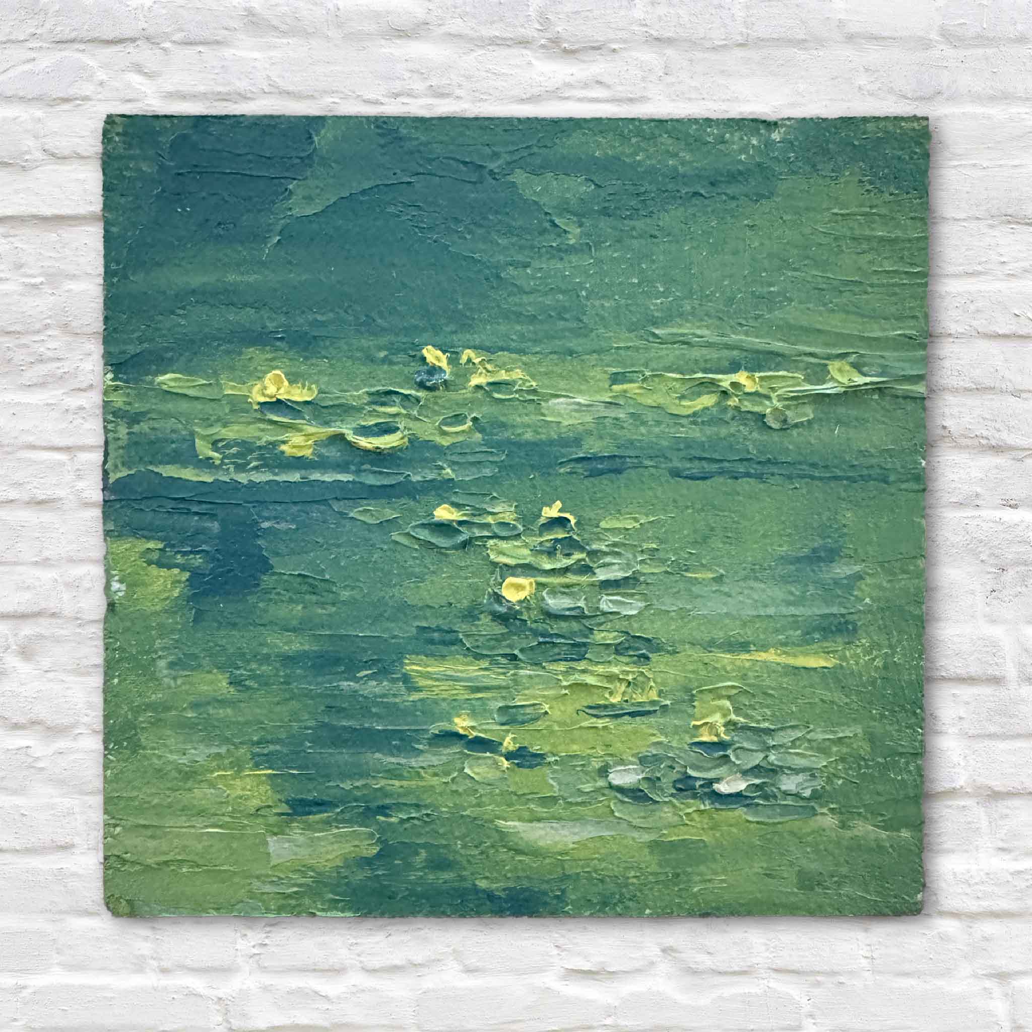 Original 3x3 oil painting of a lily pond with textured greens and yellow blooms, styled against a white brick wall in a clean, minimal setting.