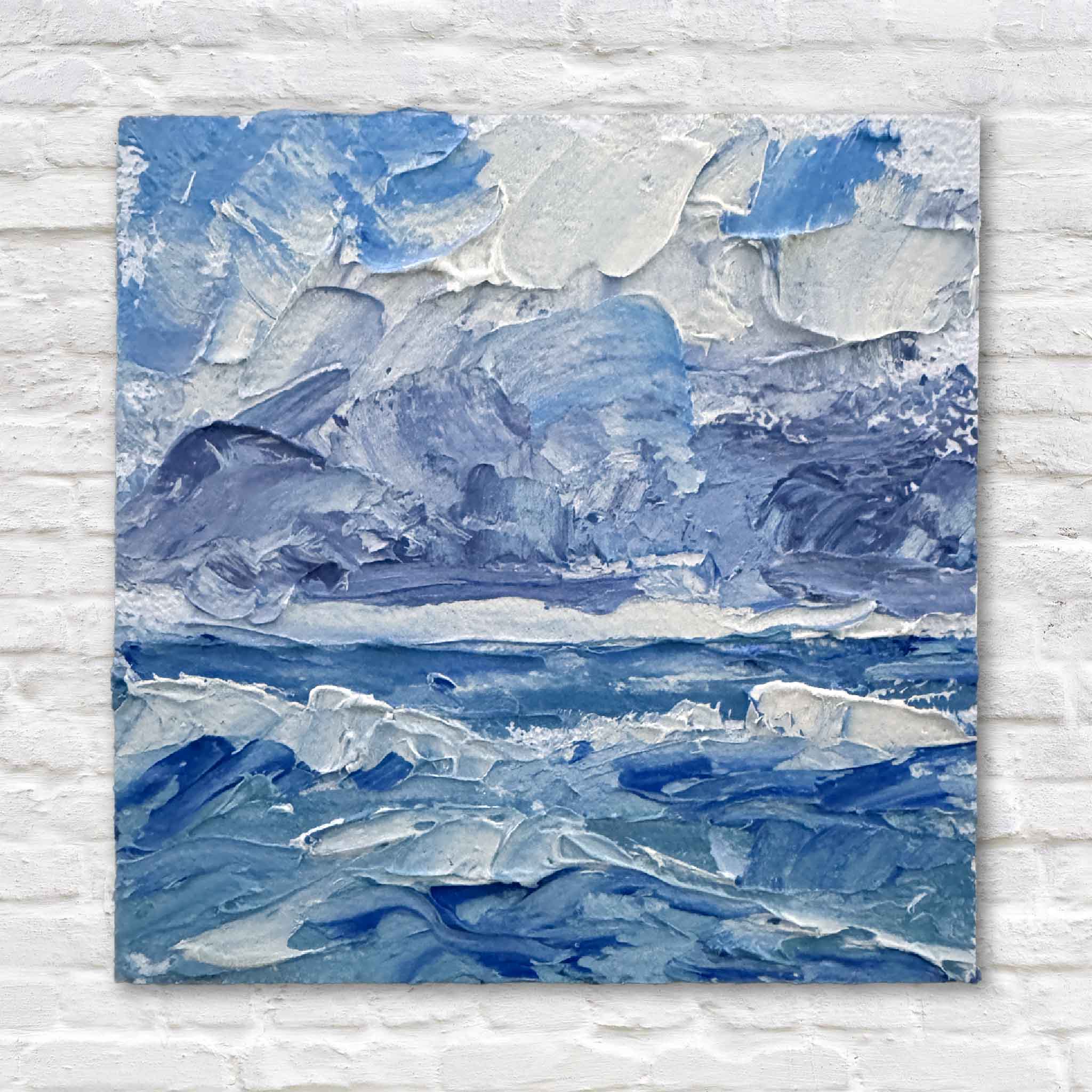 Mini 3x3 ocean oil painting with textured blue waves and clouds by local artist Joanne Willoughby, styled against a white brick wall at Gray Man Gallery.