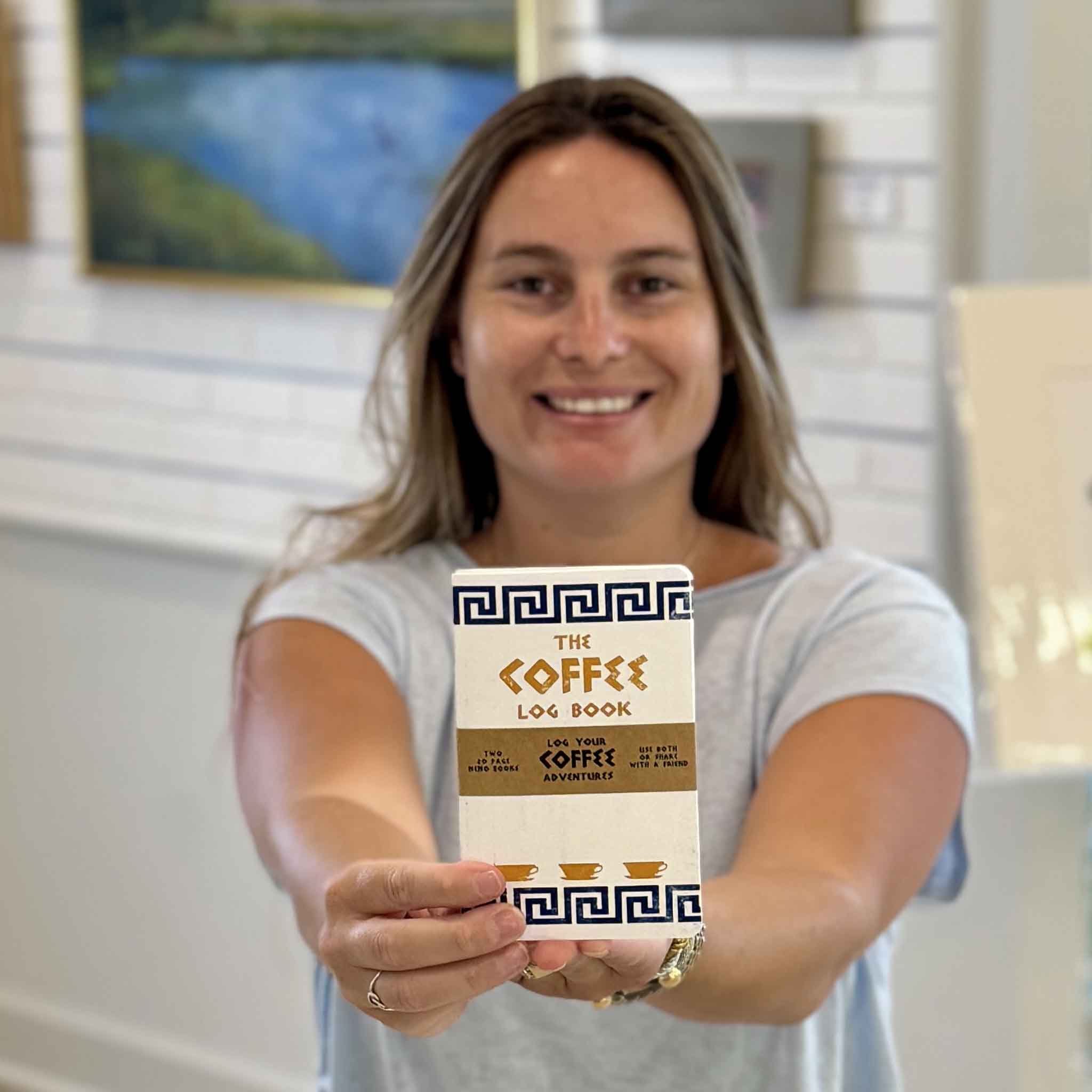 Kyra holding The Coffee Log Book by Justin Ryan Books at Gray Man Gallery in Pawleys Island, SC. This coffee tasting journal is designed for recording favorite coffees, coffee shop visits, brewing methods, roasts, flavor notes, and coffee adventures. Hand-assembled in Austin, Texas.
