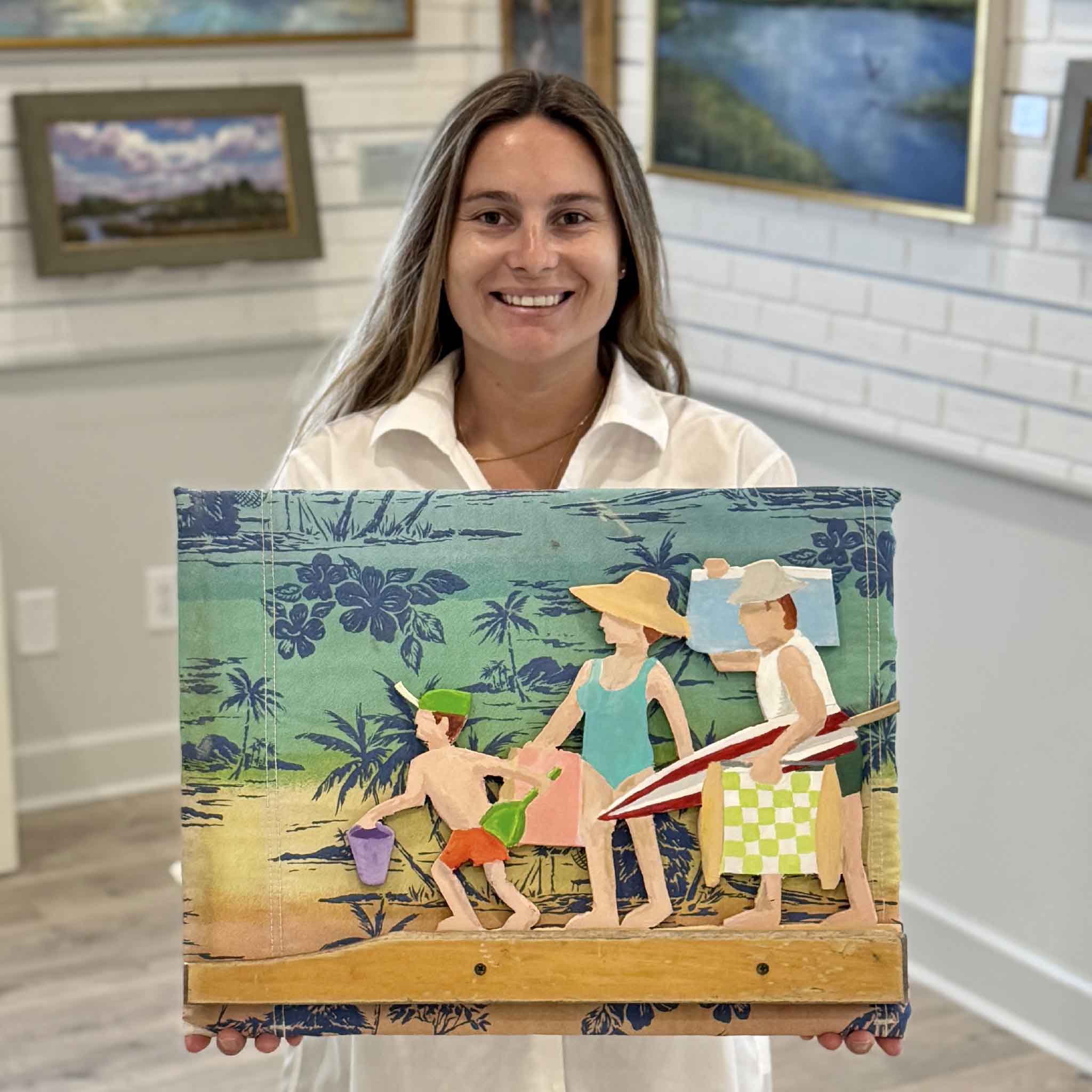 Kyra holding Family Going to the Beach, a one-of-a-kind mixed media sculpture by Charleston artist Nick Kawczynski made from reclaimed beach chair materials, marine-grade plywood, and acrylic paint at Gray Man Gallery in Pawleys Island, South Carolina.