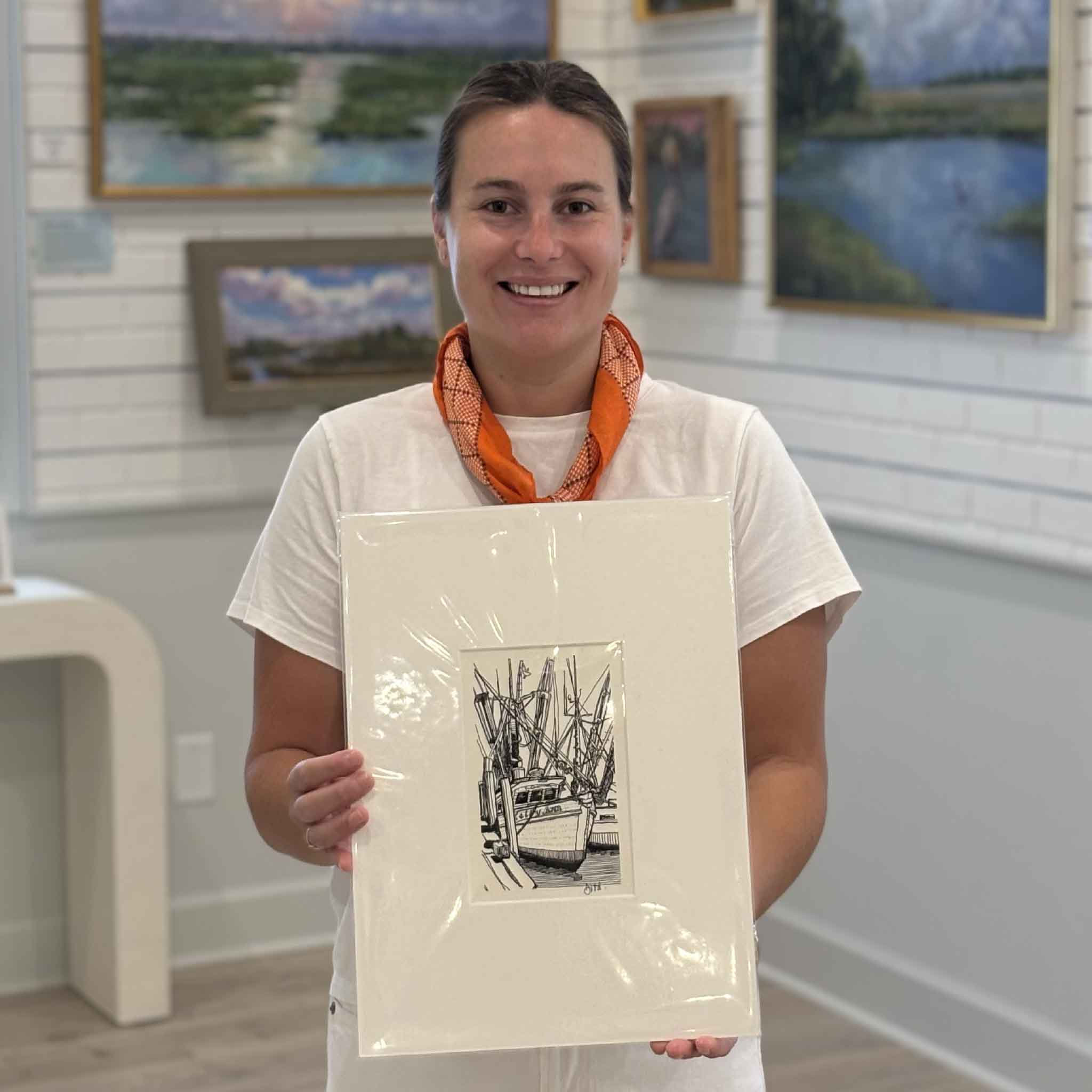Kyra holding Georgetown Shrimp Boat by Todd Halamka at Gray Man Gallery in Pawleys Island, South Carolina. This professionally matted pen-and-ink print depicts a shrimp boat docked in Georgetown Harbor and fits a standard 11x14 frame, making it an easy gift for boaters, fishermen, and Lowcountry art collectors.