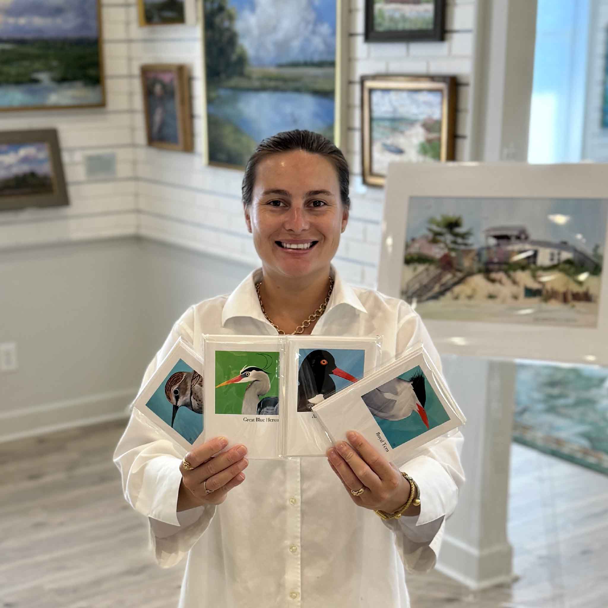 Kyra holds Nancy Jones Lowe's Lowcountry Shorebirds Notecard Set inside Gray Man Gallery in Pawleys Island, South Carolina, featuring five different folded 4x6 blank notecards with envelopes illustrated with original paintings of iconic South Carolina shorebirds.