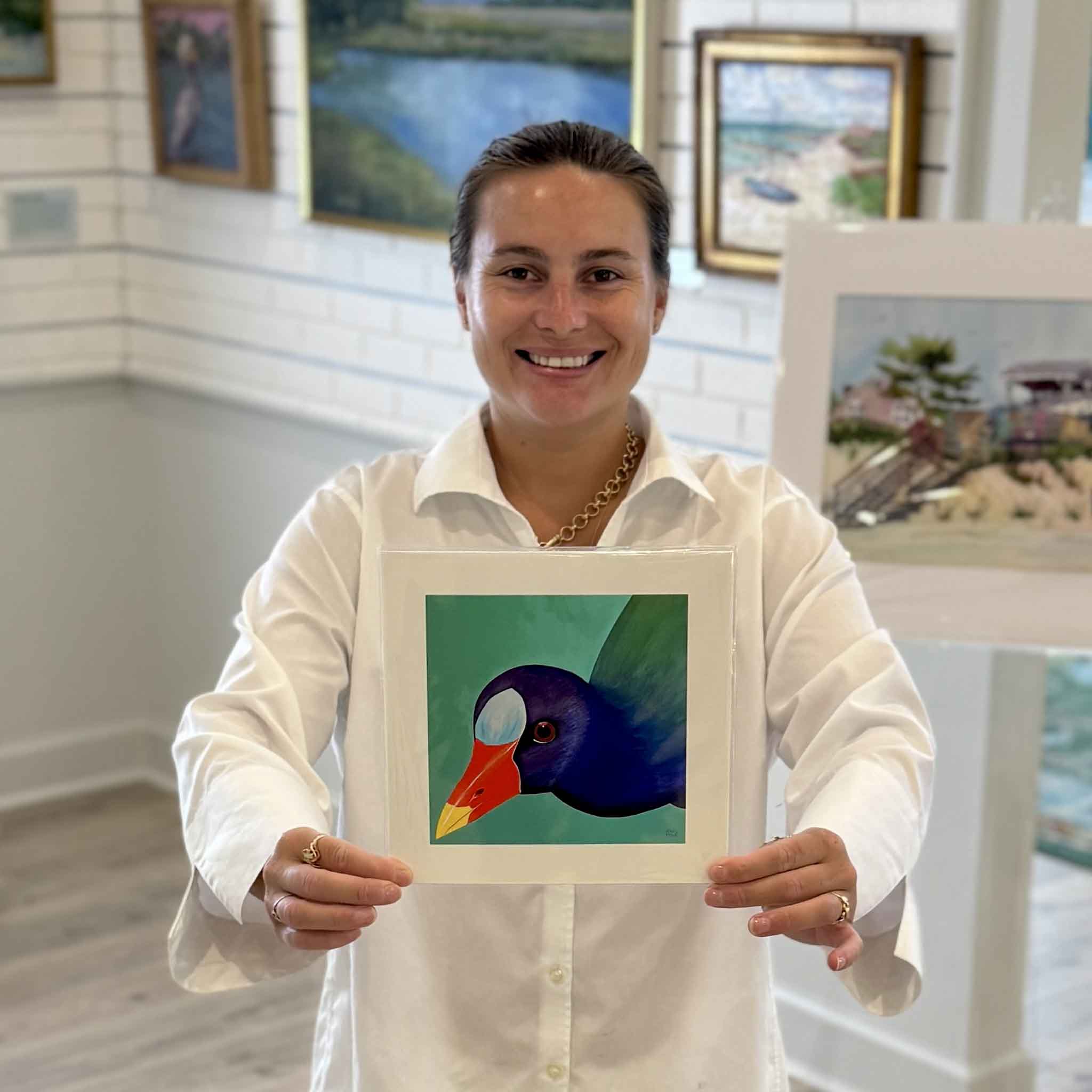 Kyra holds Purple Gallinule, an 8×8 bird print by Georgetown, South Carolina local artist Nancy Jones Lowe at Gray Man Gallery in Pawleys Island. Printed on premium 100% cotton archival fine art paper with archival pigment inks, this colorful Lowcountry bird print fits any standard 8×8 frame without custom framing.