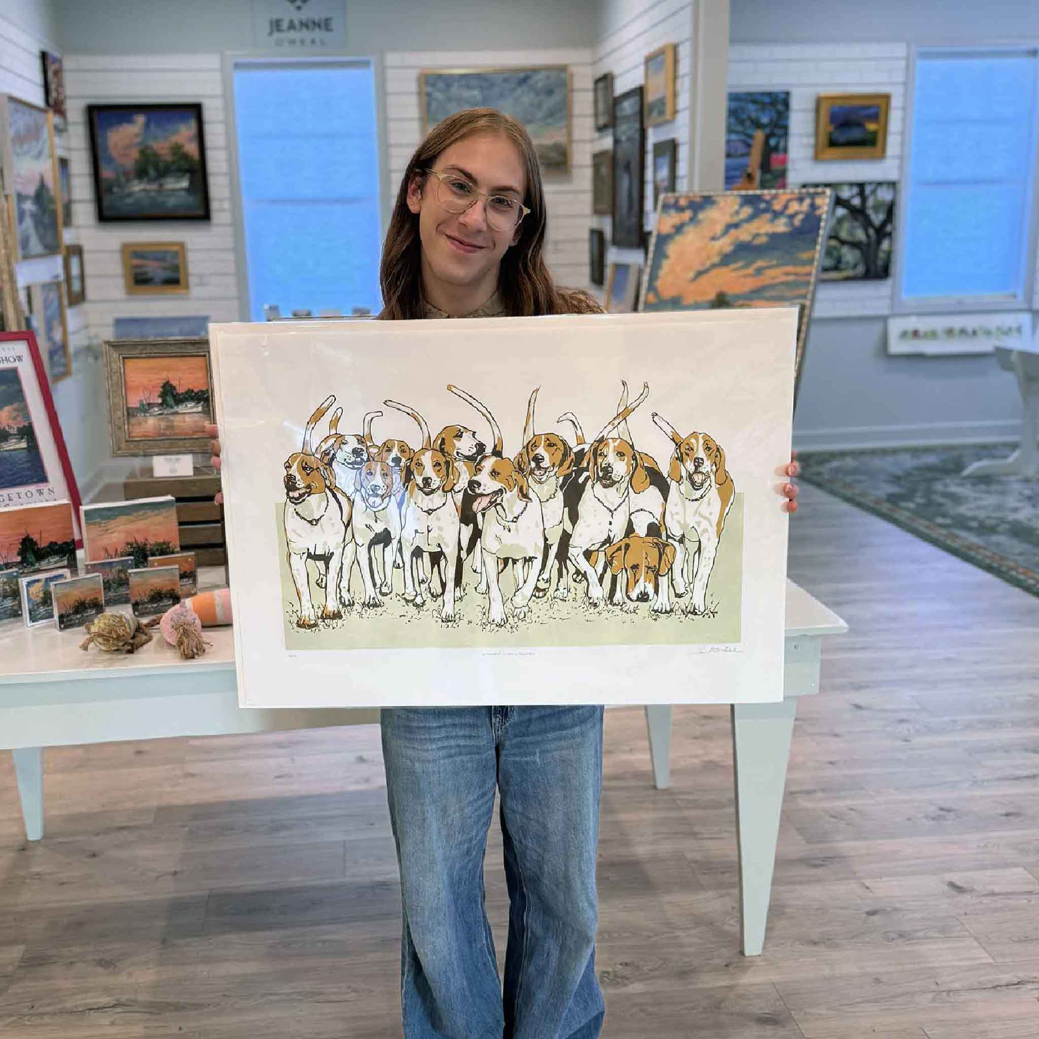 Original linocut “A Dozen Happy Hounds” by Laurie McIntosh held at Gray Man Gallery, featuring twelve lively running hounds in warm, earthy tones.