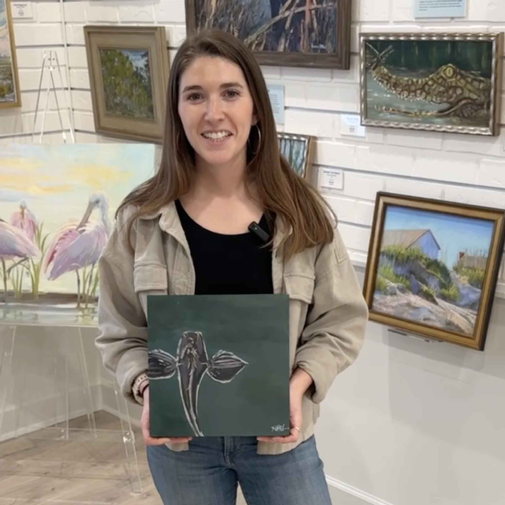 Local artist Maggie Pelton holding her original painting “Night Fishing” inside Gray Man Gallery in Pawleys Island, South Carolina, showcasing Lowcountry coastal artwork and custom framing by the island’s oldest art gallery