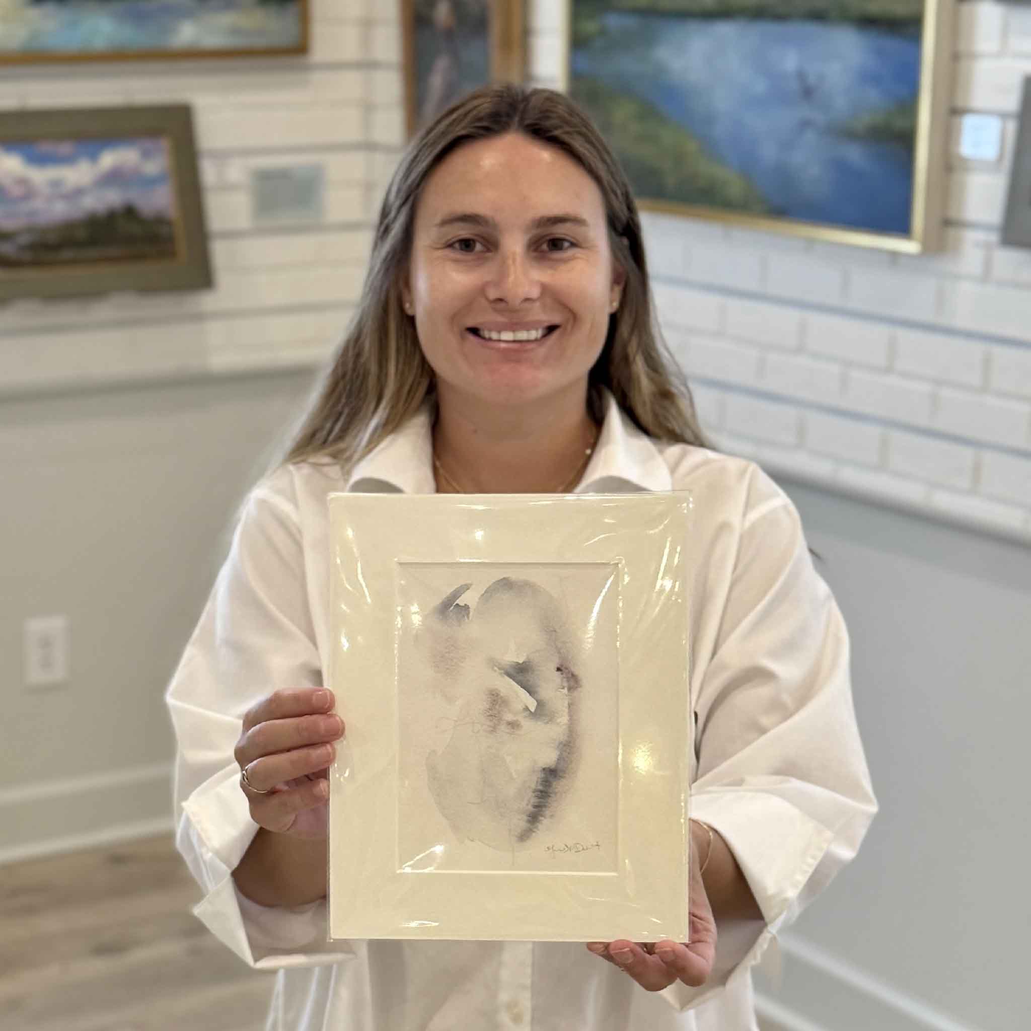 Kyra holds Tidal Study III, an original oyster-inspired watercolor by Lowcountry artist Megan DuMont. This one-of-a-kind abstract painting features soft coastal tones, layered watercolor washes, and organic forms inspired by South Carolina oyster shells. Professionally matted to fit a standard 8x10 frame and available at Gray Man Gallery in Pawleys Island, SC.