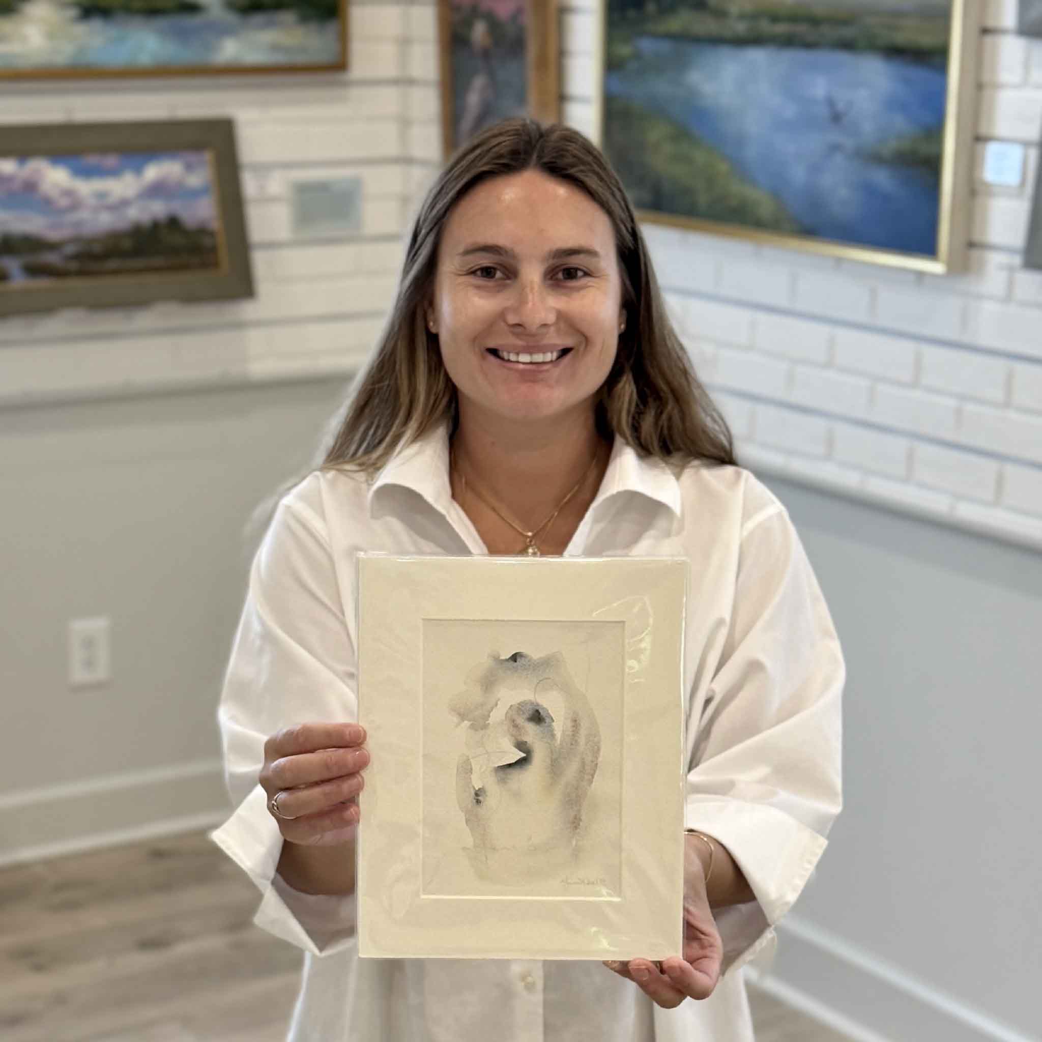 Kyra holds Tidal Study IV, an original oyster-inspired watercolor by Lowcountry artist Megan DuMont. This one-of-a-kind abstract painting features soft coastal tones, flowing organic forms, and layered watercolor washes inspired by South Carolina oyster shells. Professionally matted to fit a standard 8x10 frame and available at Gray Man Gallery in Pawleys Island, SC.