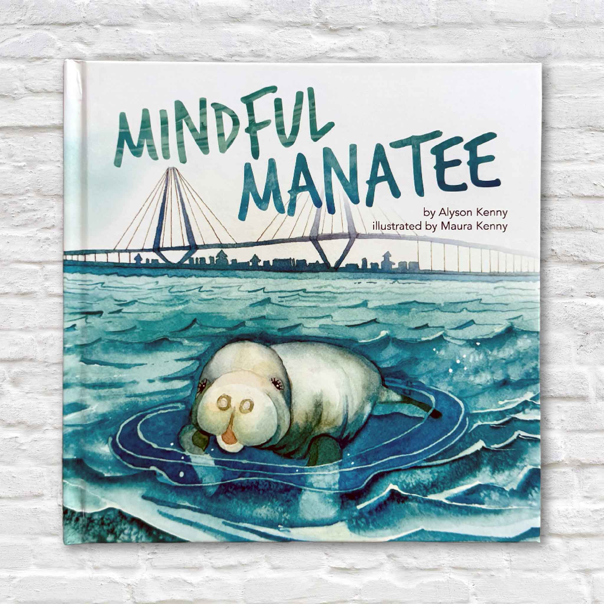 Mindful Manatee children’s book displayed against a white brick background, featuring a watercolor manatee in coastal blue water illustrated by Maura Kenny.