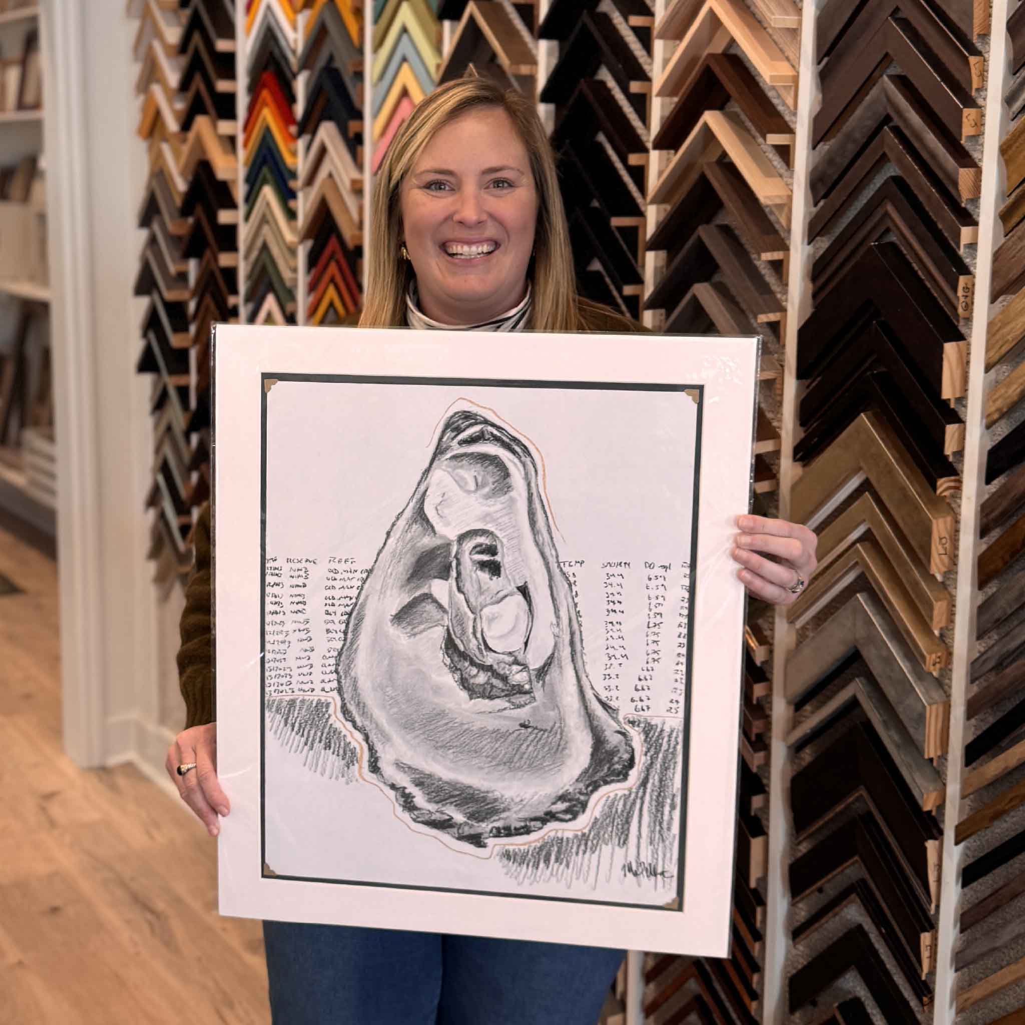 “North Inlet Oyster,” an original charcoal drawing shown held inside Gray Man Gallery to demonstrate scale and presentation, featuring a detailed oyster study inspired by South Carolina coastal ecology and water quality research