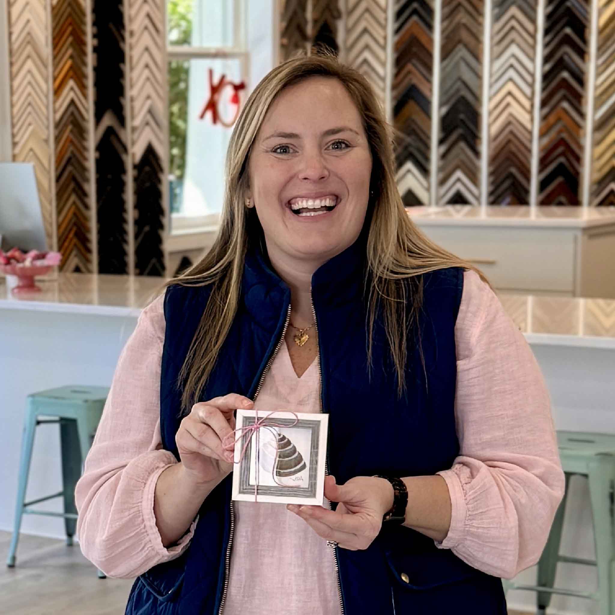 Bordy holding Pawleys Island Shell original watercolor by local Pawleys Island artist Vida Miller at Gray Man Gallery, small 3x3 framed coastal shell artwork with easel back, giftable Lowcountry art inspired by shells found on the beach