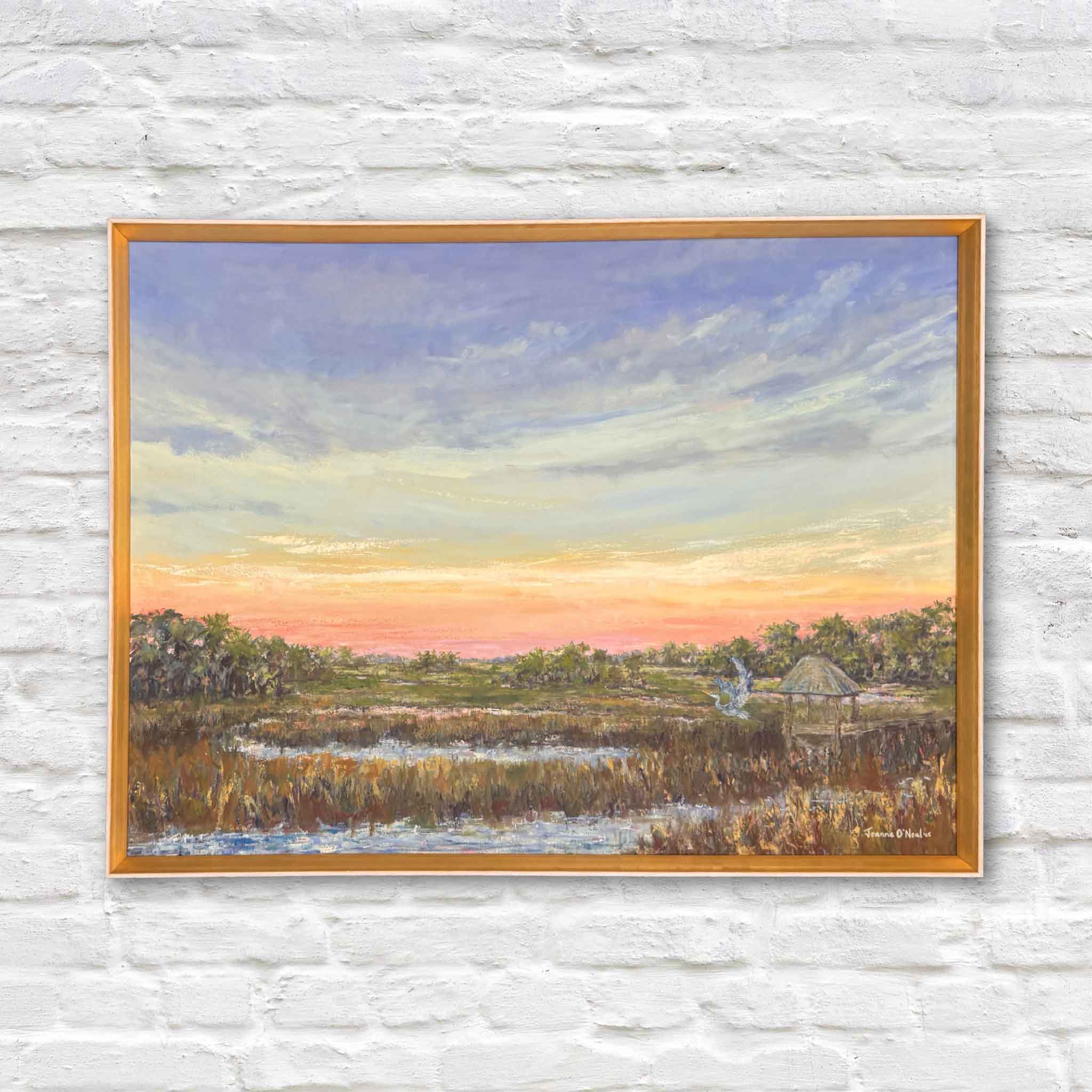 Original oil painting titled Peach Moonshine by local Lowcountry artist Jeanne O’Neal, framed in signature gold frame, featuring pastel sunset sky over South Carolina marsh with heron and tidal creek, displayed at Gray Man Gallery in Pawleys Island