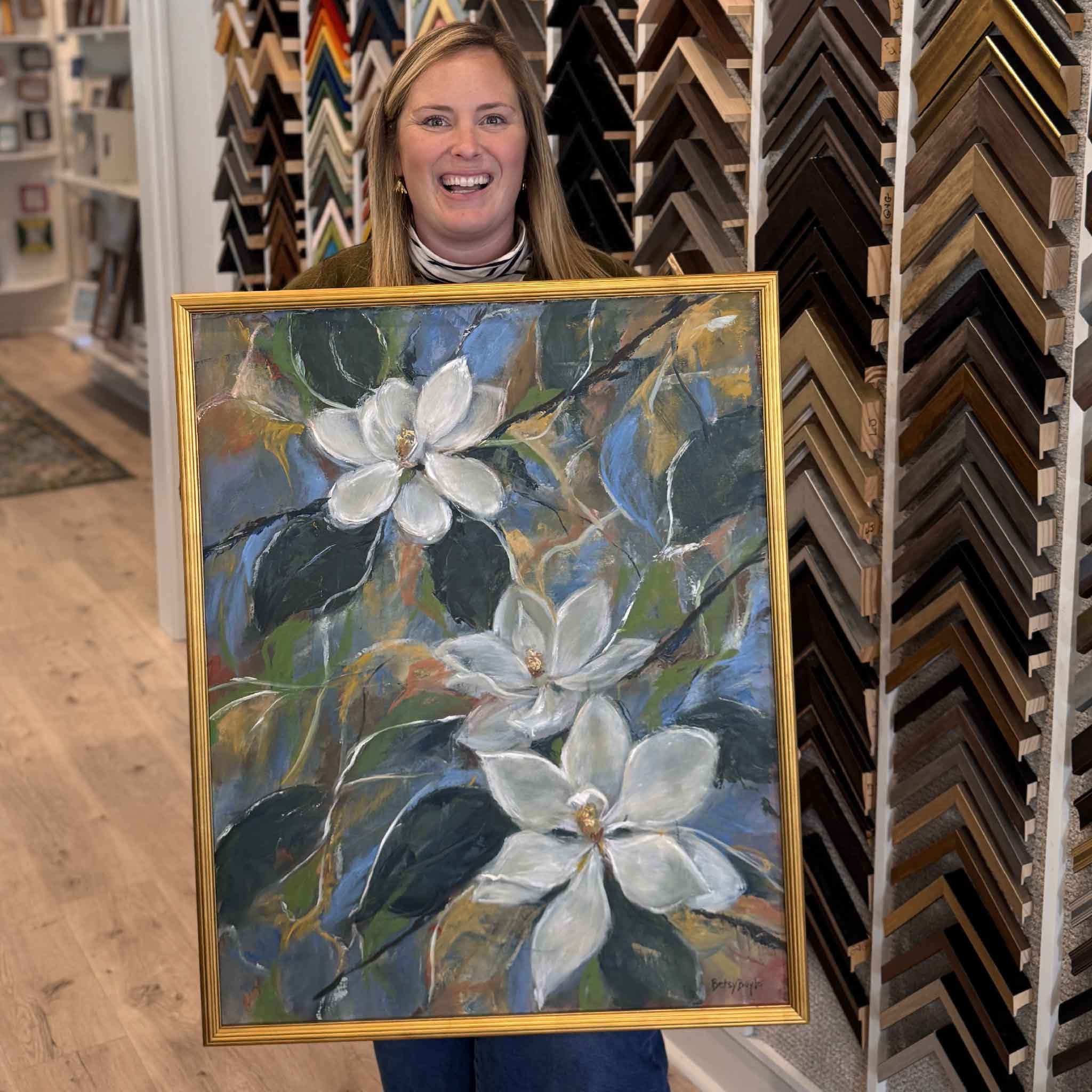 Perfect and Pure by local artist Betsy Boyle, original magnolia oil painting shown framed and held inside Gray Man Gallery in Pawleys Island, SC