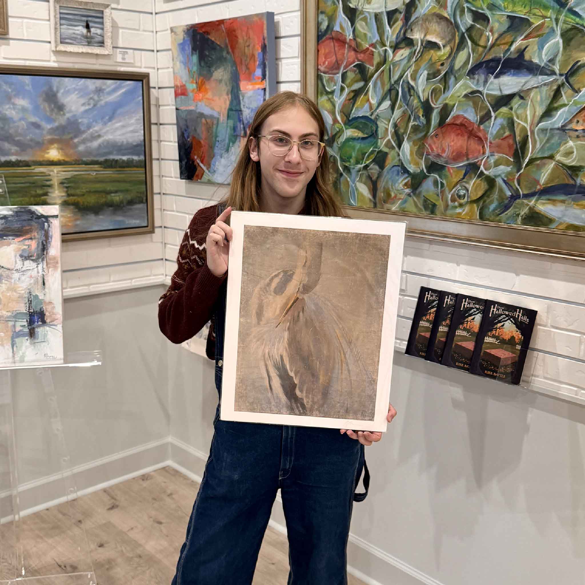 Gray Man Gallery staff member holding the Phoenix Rising heron giclée print by Helli Luck inside the art gallery.