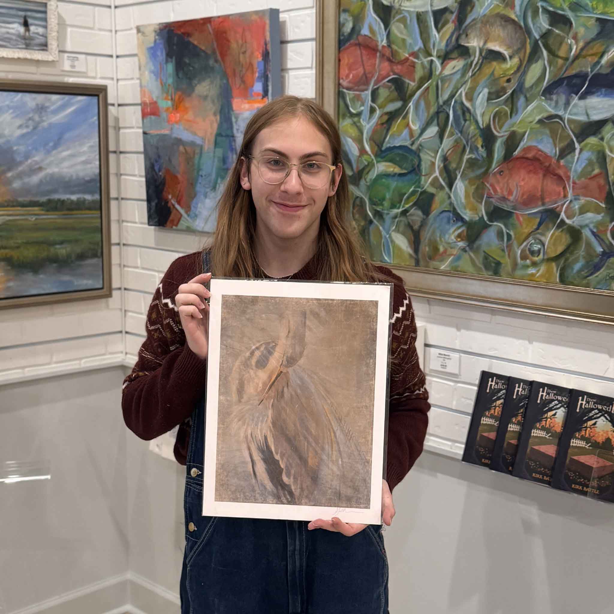 Gray Man Gallery staff member holding the Phoenix Rising heron giclée print by Helli Luck inside the art gallery.