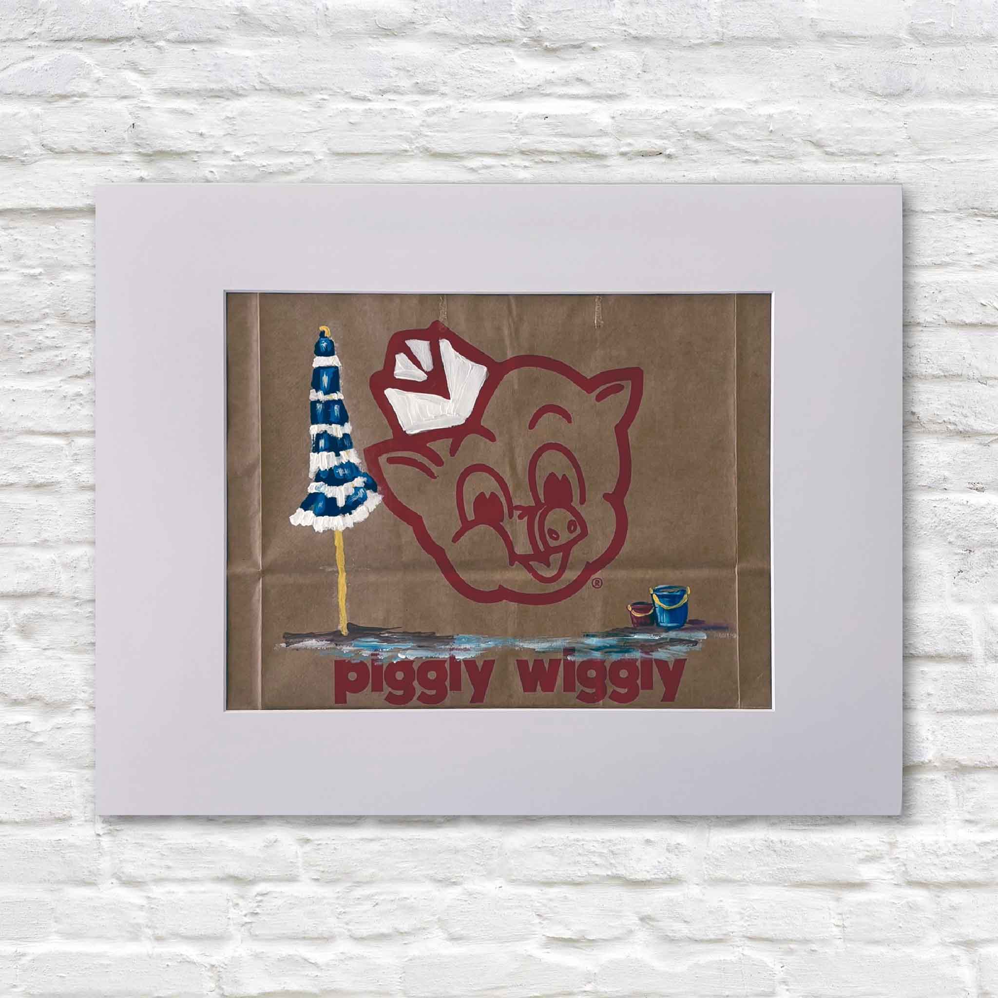 Piggly Wiggly Beach Day painting by local artist Jenny Reynolds on an authentic grocery bag featuring pig logo, blue striped umbrella, and sand bucket at Gray Man Gallery Pawleys Island