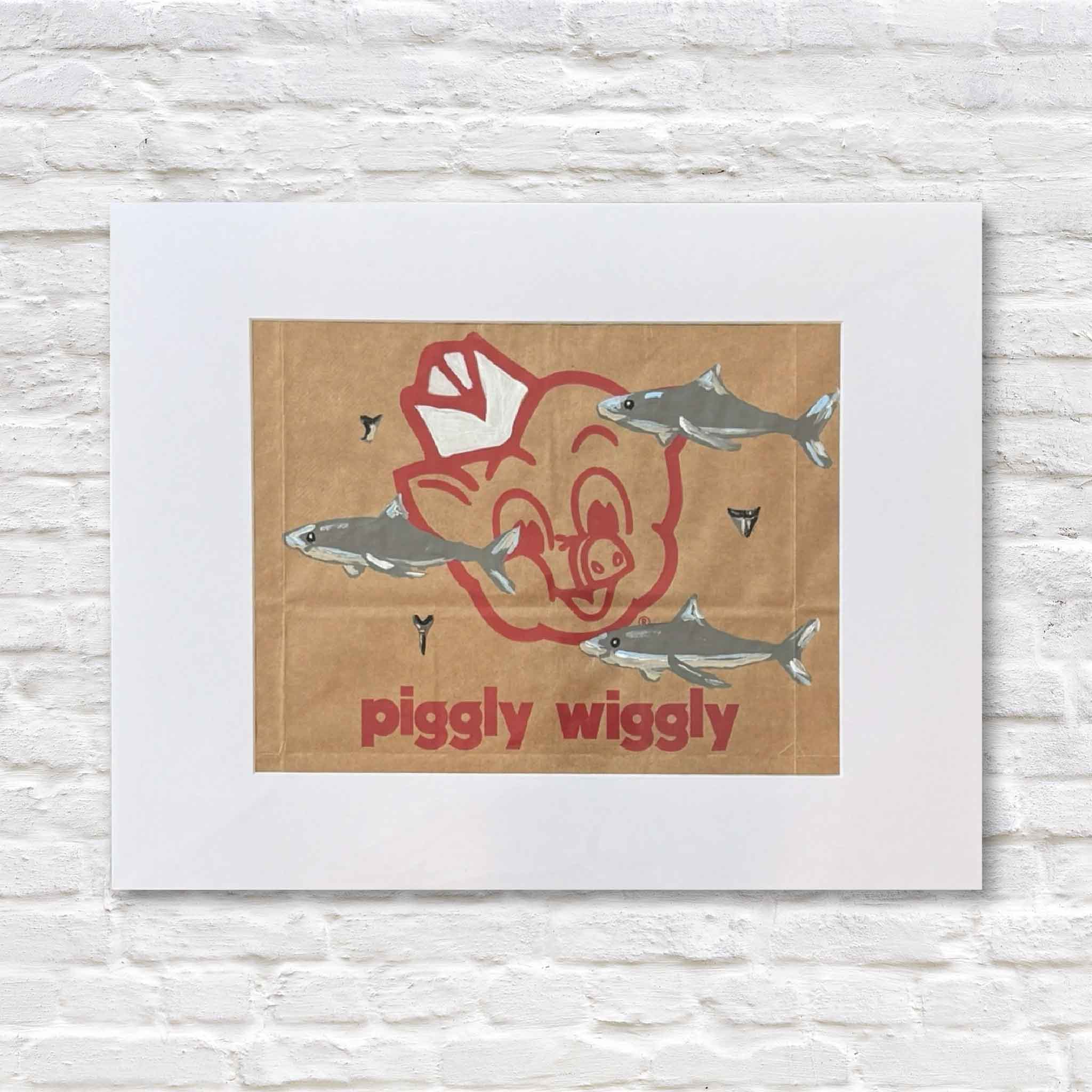 Jenny Reynolds’ Piggly Wiggly “Sharksl” artwork painted on a grocery bag, featuring the classic logo with swimming sharks, shown matted for scale inside Gray Man Gallery.