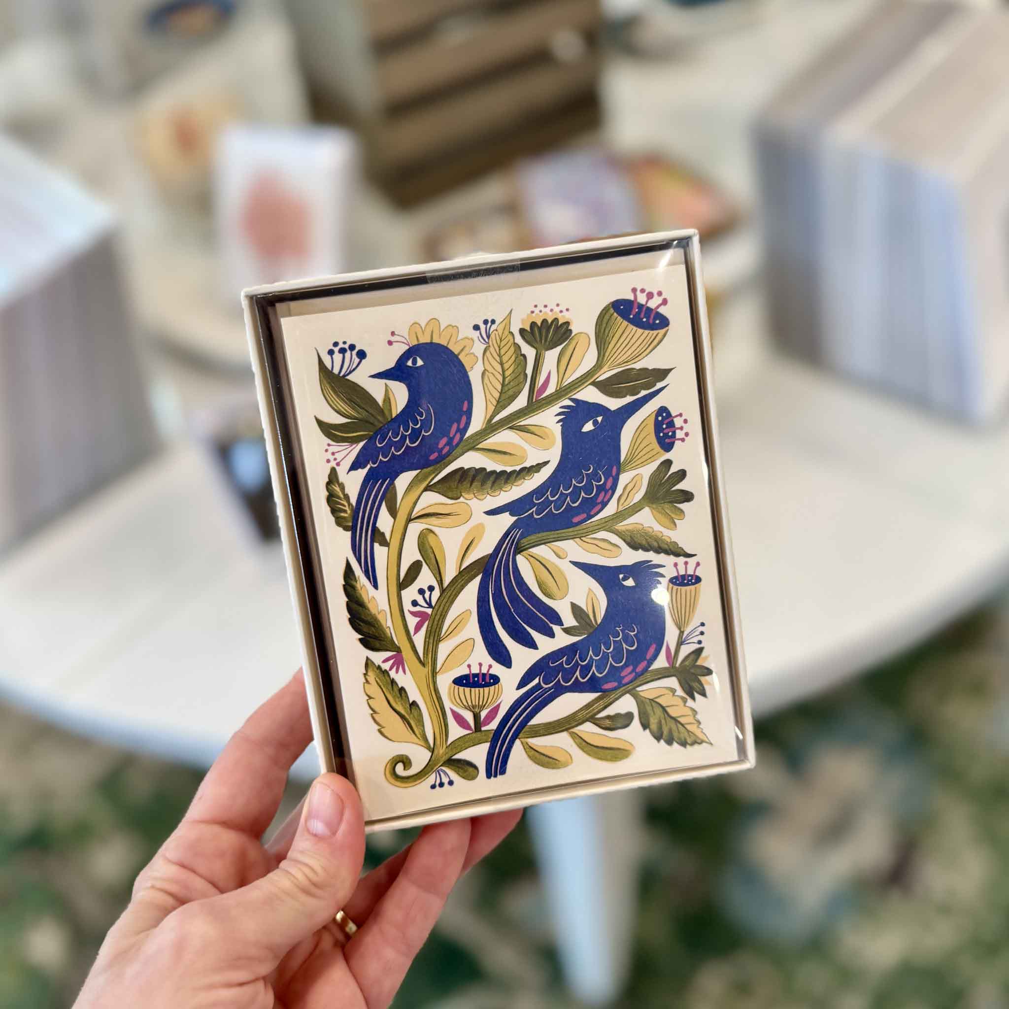 Purple Birds botanical notecard by Melissa Castrillon held inside Gray Man Gallery in Pawleys Island, showing the detailed blue bird, floral, and foliage illustration included in the boxed set of eight.