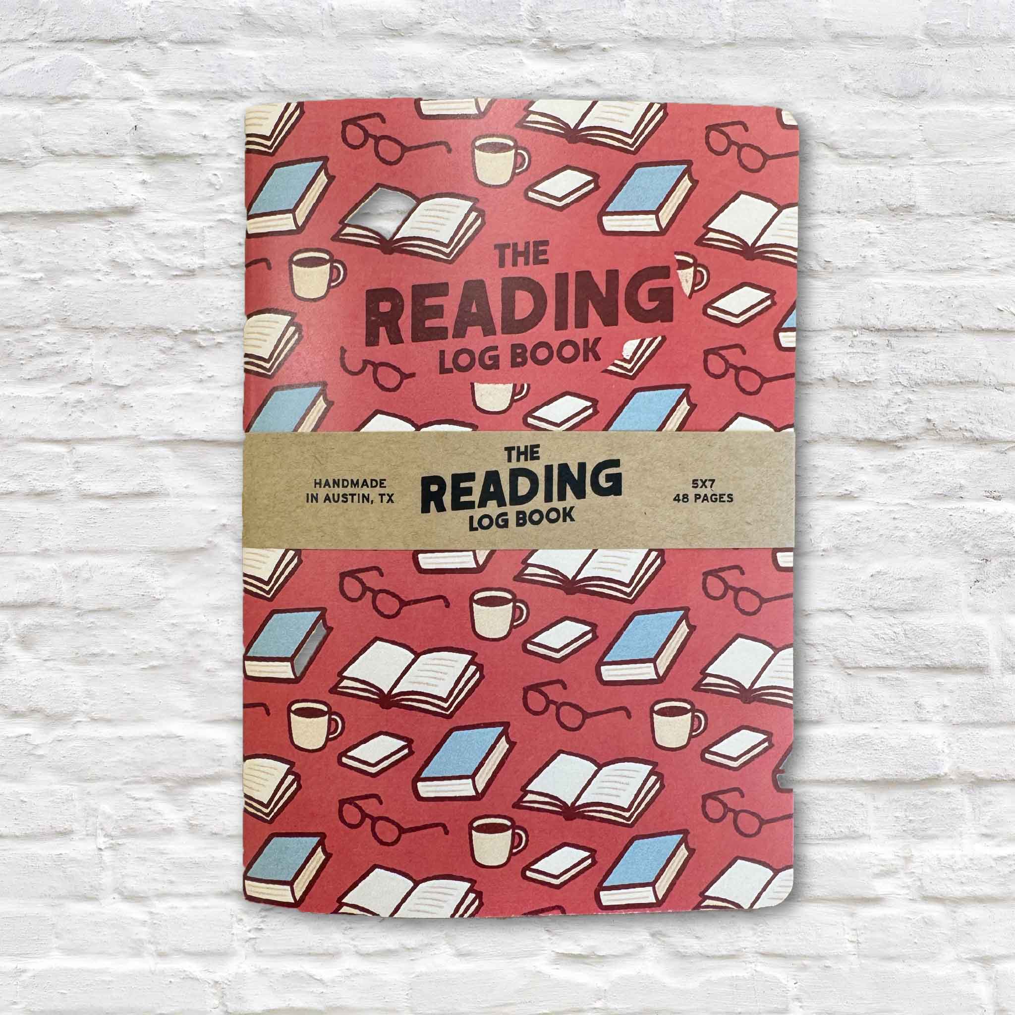The Reading Log Book, a 5x7 reading journal featuring a colorful pattern of books, coffee mugs, and reading glasses. This 48-page journal helps readers track books, favorite quotes, ratings, reviews, reading dates, and personal reflections. Available at Gray Man Gallery in Pawleys Island, South Carolina.