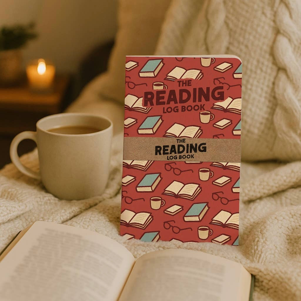 The Reading Log Book displayed beside an open book, coffee mug, and cozy blanket. This 5x7 reading journal is perfect for tracking books, recording favorite quotes, writing reviews, and creating a lasting record of your reading life.