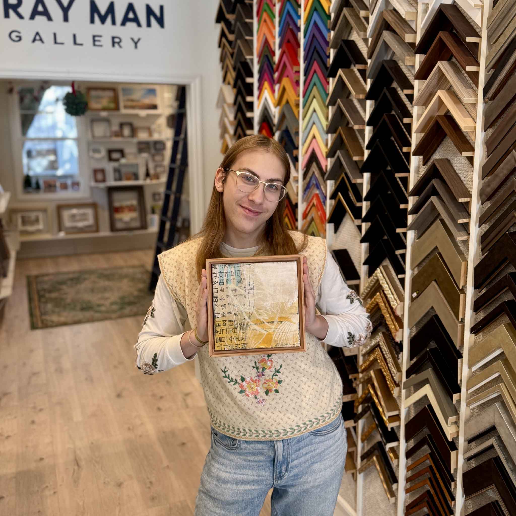 Team member holding the 8x8 Residuals 5D artwork to show size and scale, highlighting the layered markings and rustic wooden floater frame.