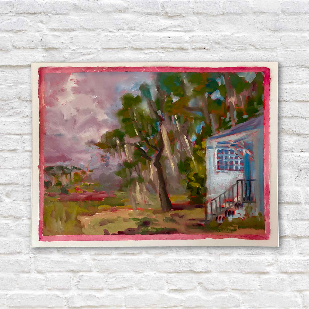 Stormy Jamie’s #215 original oil on paper by local artist Retta Dotterer featuring a white Lowcountry building, live oaks, Spanish moss and a stormy lavender sky with a hand-painted pink border at Gray Man Gallery in Pawleys Island.