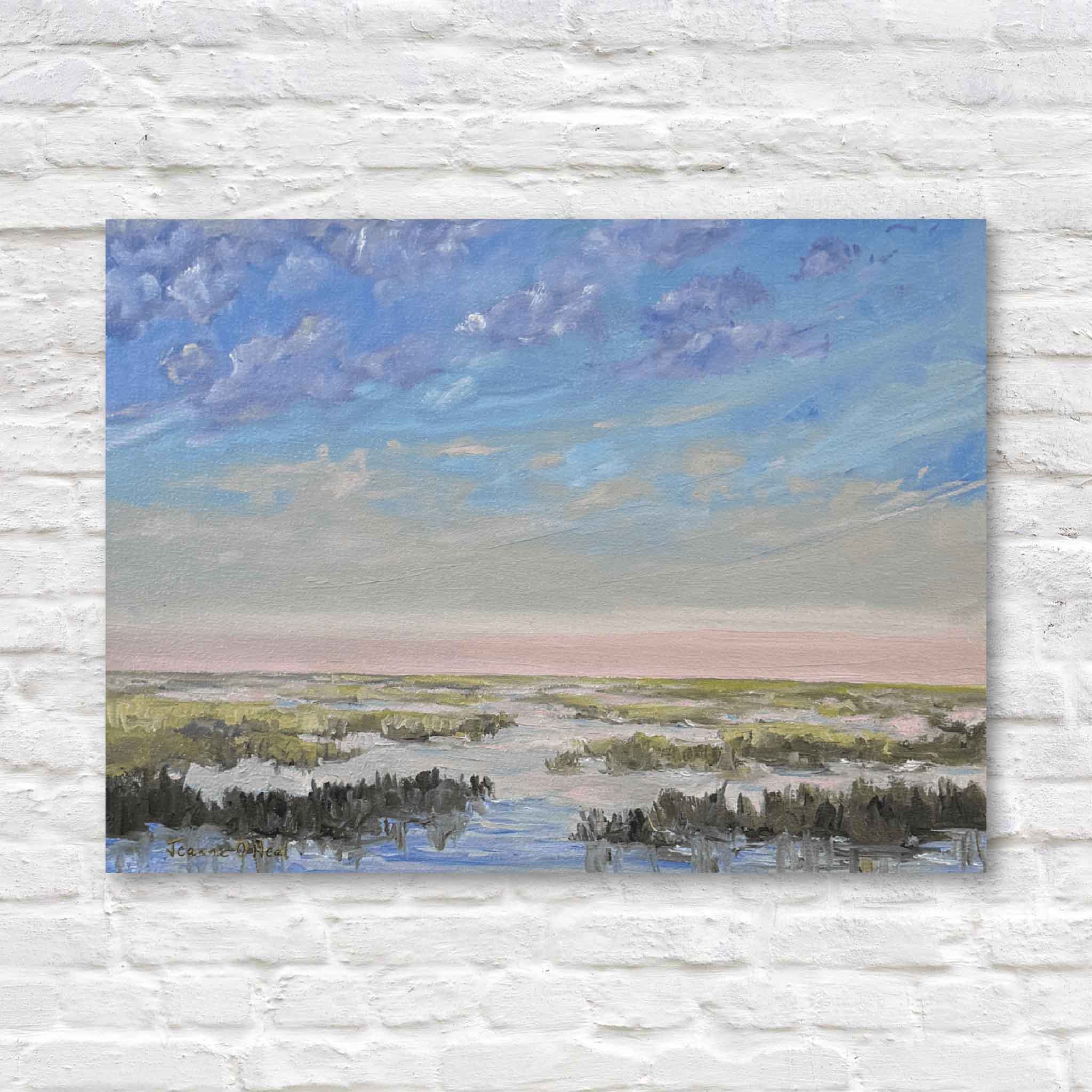 This image shows Salt + Light #7, a coastal marsh painting by Jeanne O’Neal featuring soft pastel skies, tranquil tidal creeks, and gentle Lowcountry light displayed against a white brick background.
