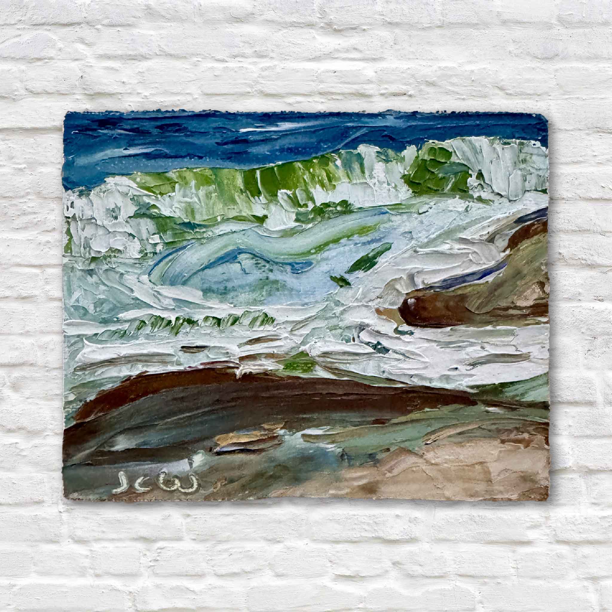 This photo shows Seabreeze, an original miniature oil painting by Joanne Willoughby, displayed on a small wooden easel with textured coastal brushstrokes in blues, greens, and sandy browns.
