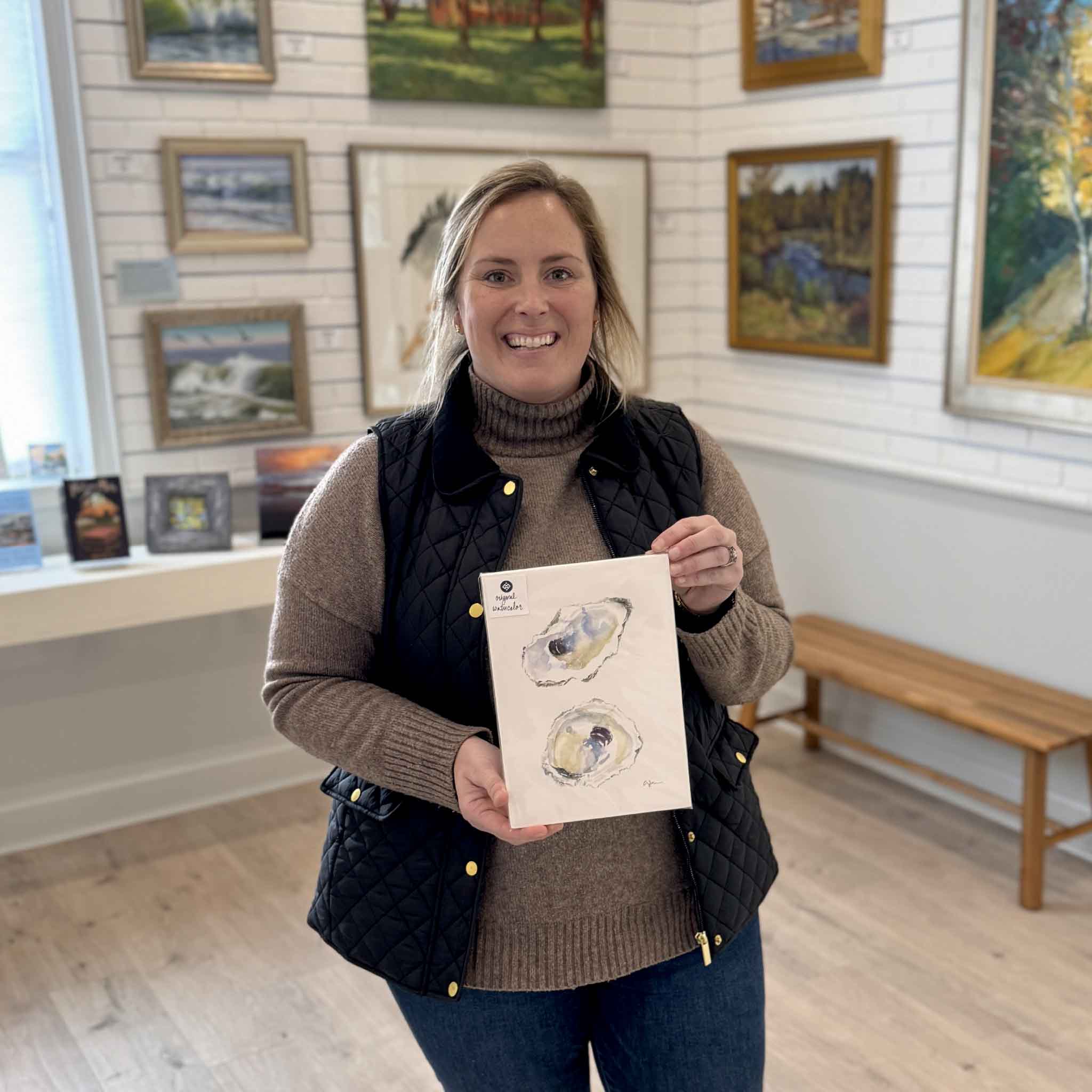 Bordy holding original watercolor oyster painting “Serendipity” by local artist Allison Farr inside Gray Man Gallery in Pawleys Island, part of the Lowcountry Jewels series