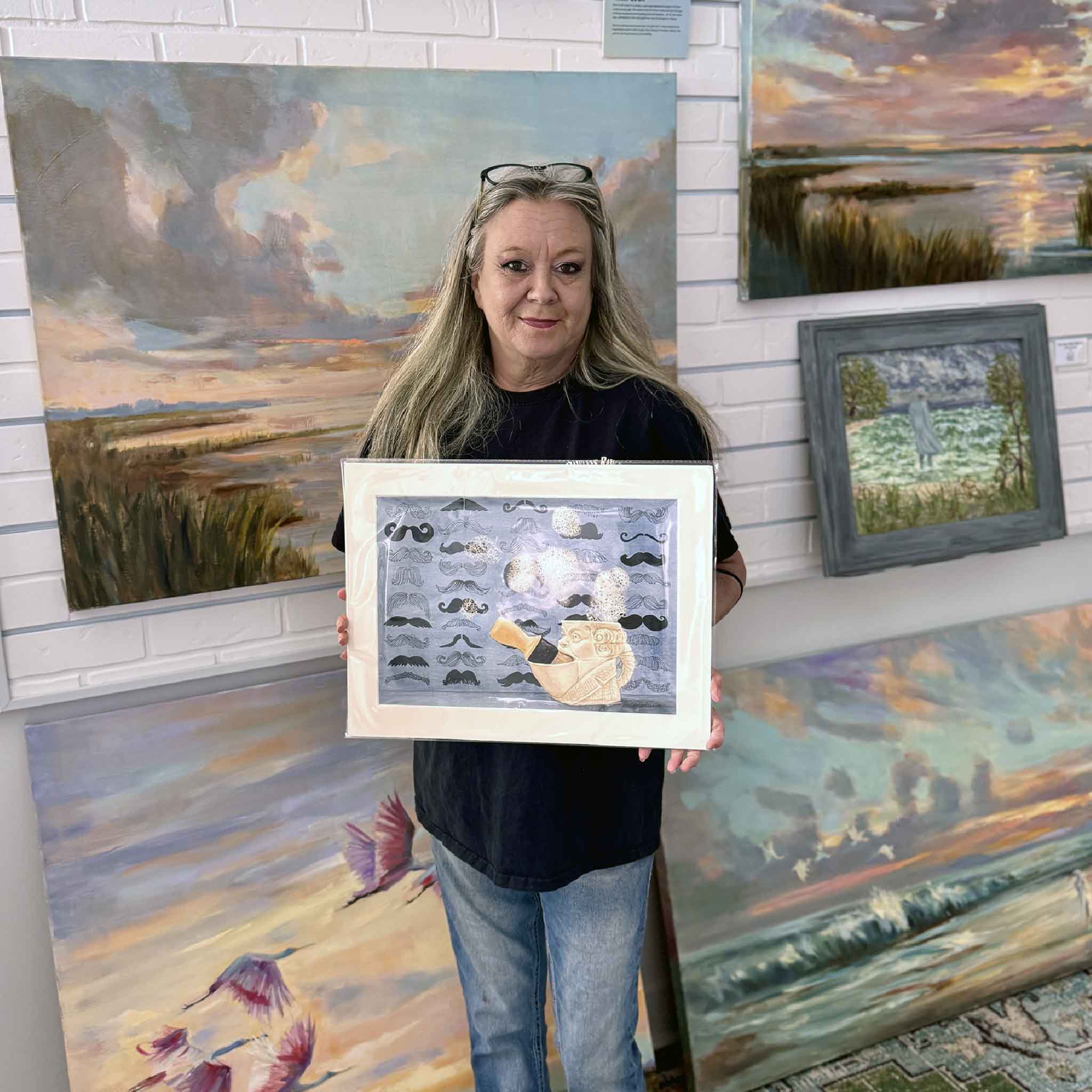 A Gray Man Gallery team member holds Shave Time by Mimi Beaver, an original watercolor artwork donated in full support of Salty Dogs Senior Animal Rescue, with all proceeds benefiting senior dogs.