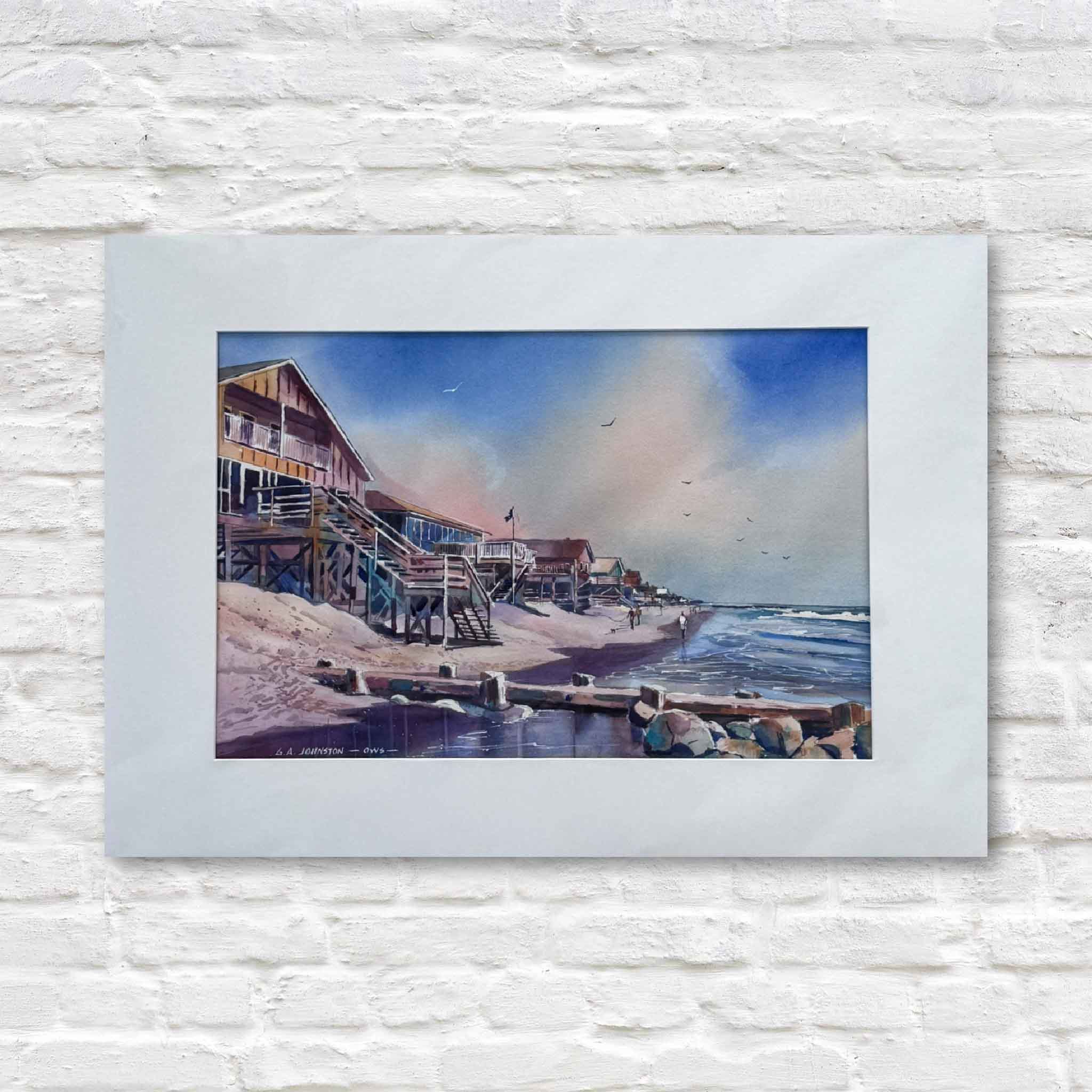 A matted watercolor by Gary Johnston depicting Pawleys Island’s South End with classic stilted beach houses, soft pastel skies, and waves rolling onto the shore.