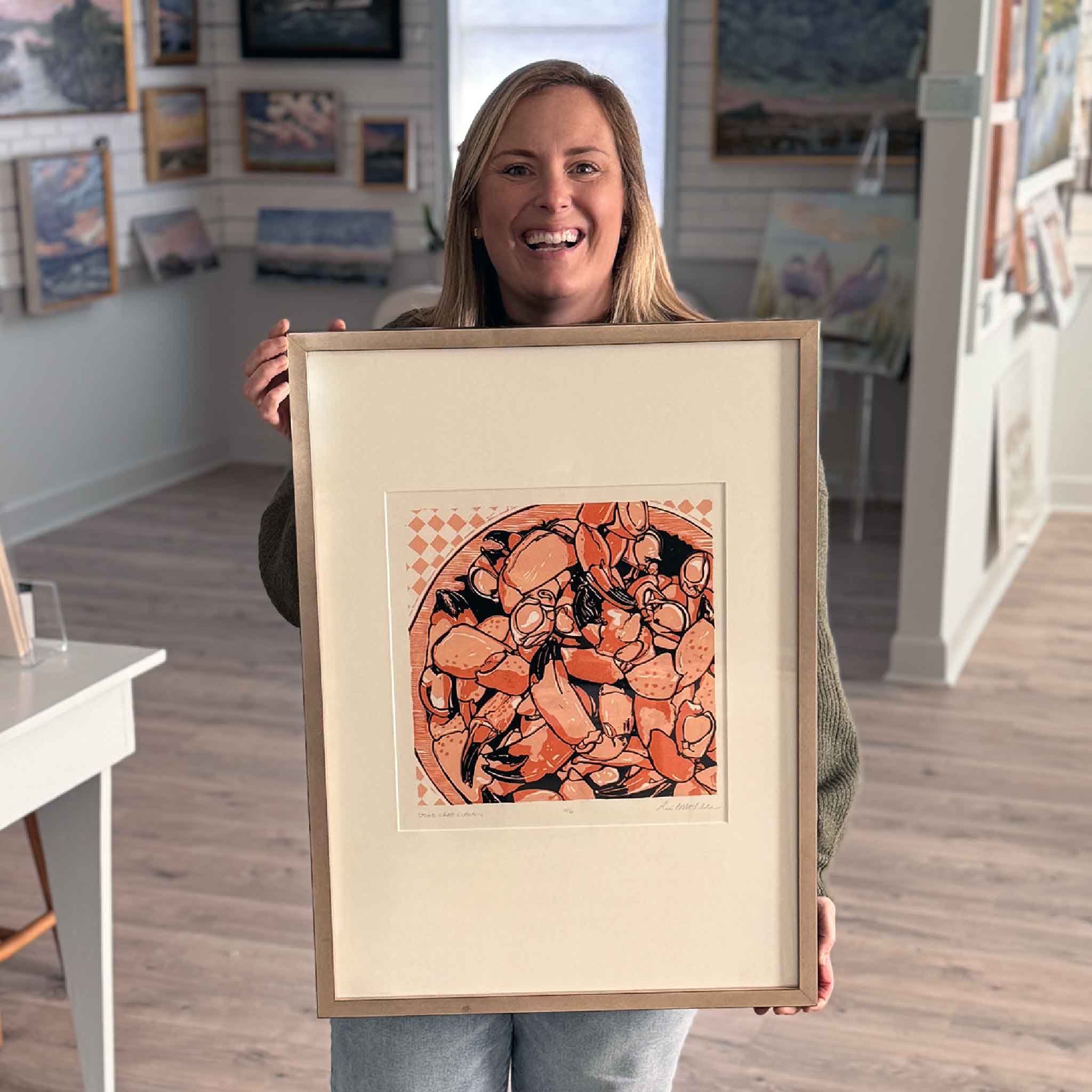 Bordy from Gray Man Gallery holding Stone Crab Claws by local artist Laurie McIntosh to show scale inside the gallery.