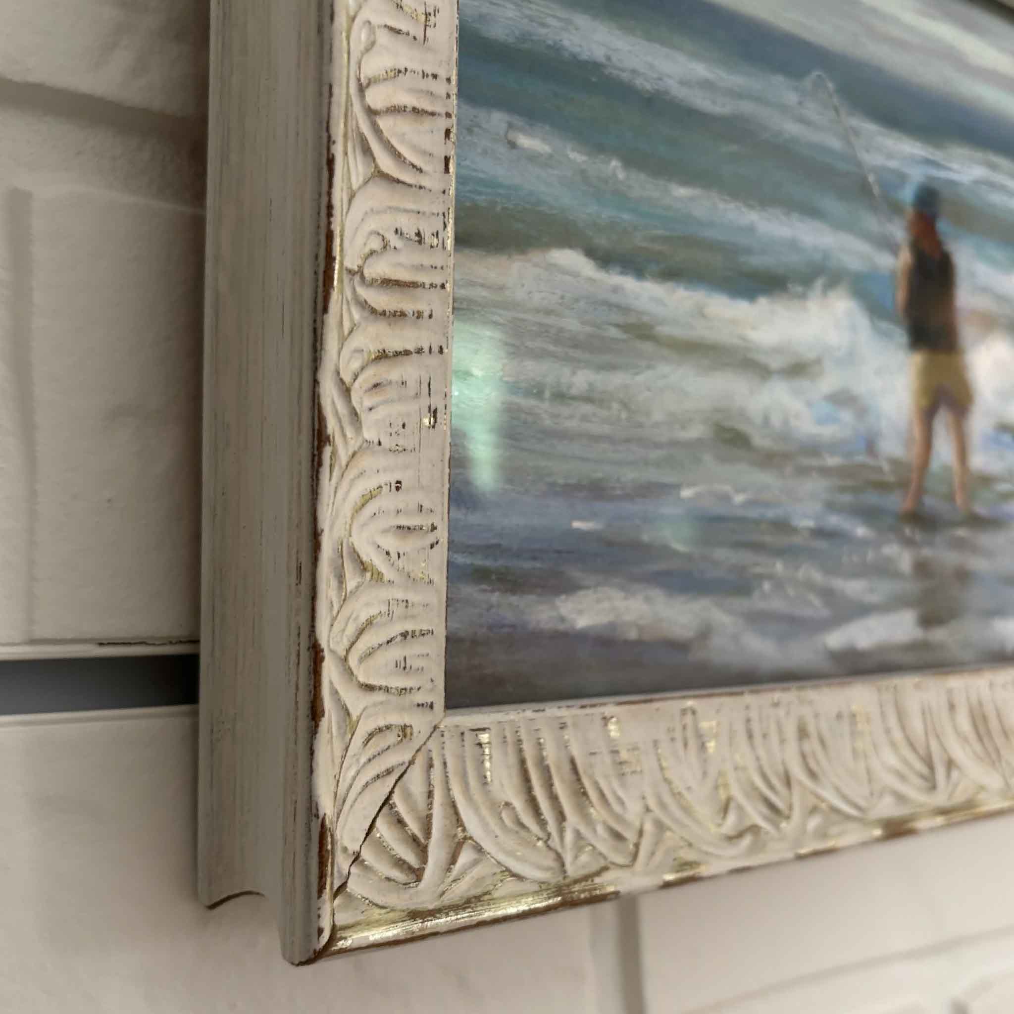Side view of the framed original pastel Surf Casting by Joanne Willoughby showing the ornate whitewashed carved frame and coastal artwork at Gray Man Gallery in Pawleys Island
