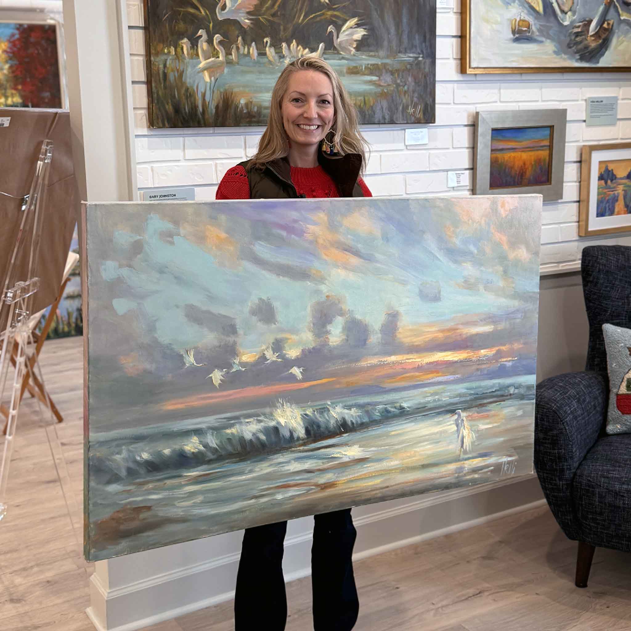 Local artist Jeanne O'Neal holding the oversized 48x30 painting The Lookout by Helli Luck in the gallery to show its impressive scale.