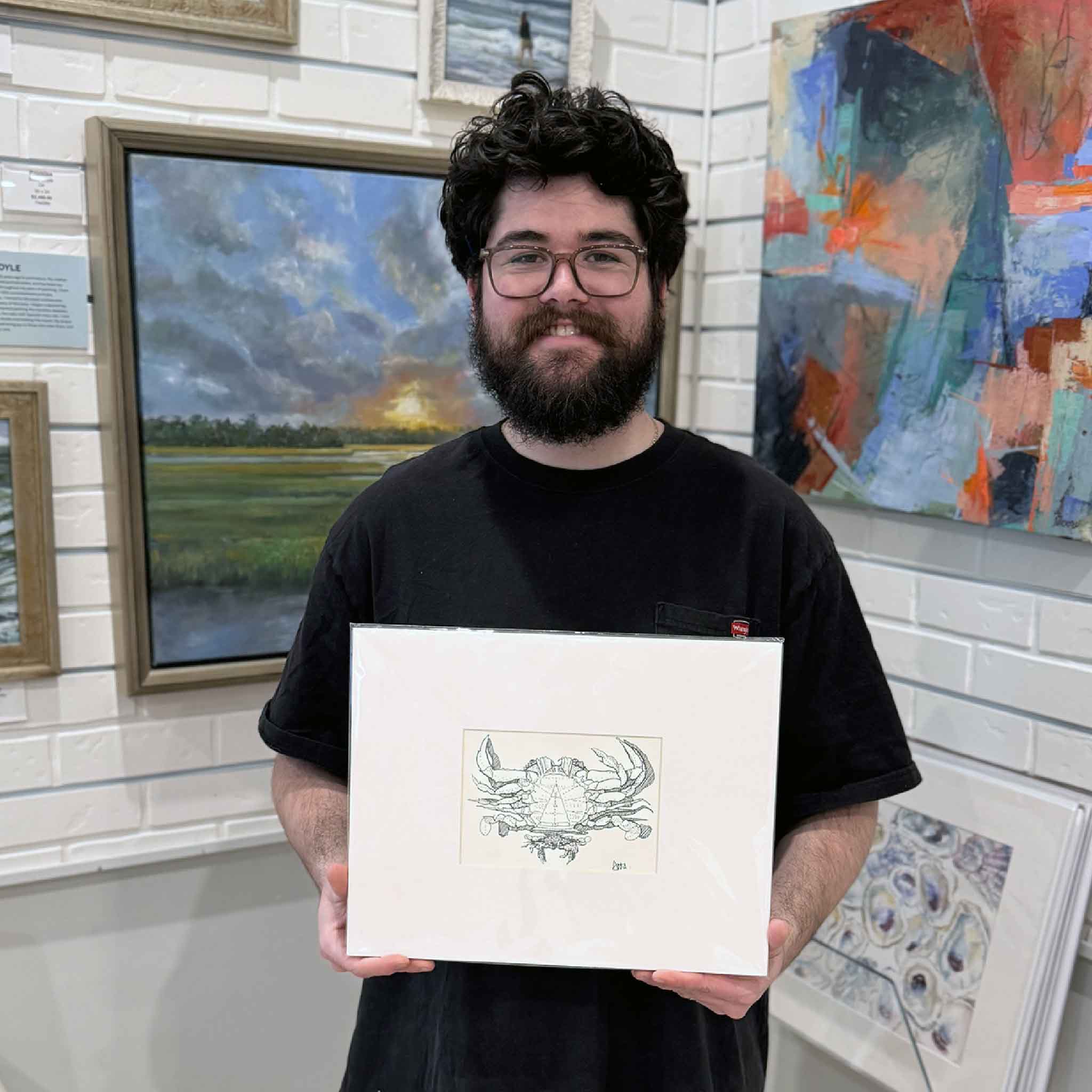 Gallery team member holding the matted Blue Crab Study print by Lowcountry artist Todd Halamka inside Gray Man Gallery with artwork in the background.