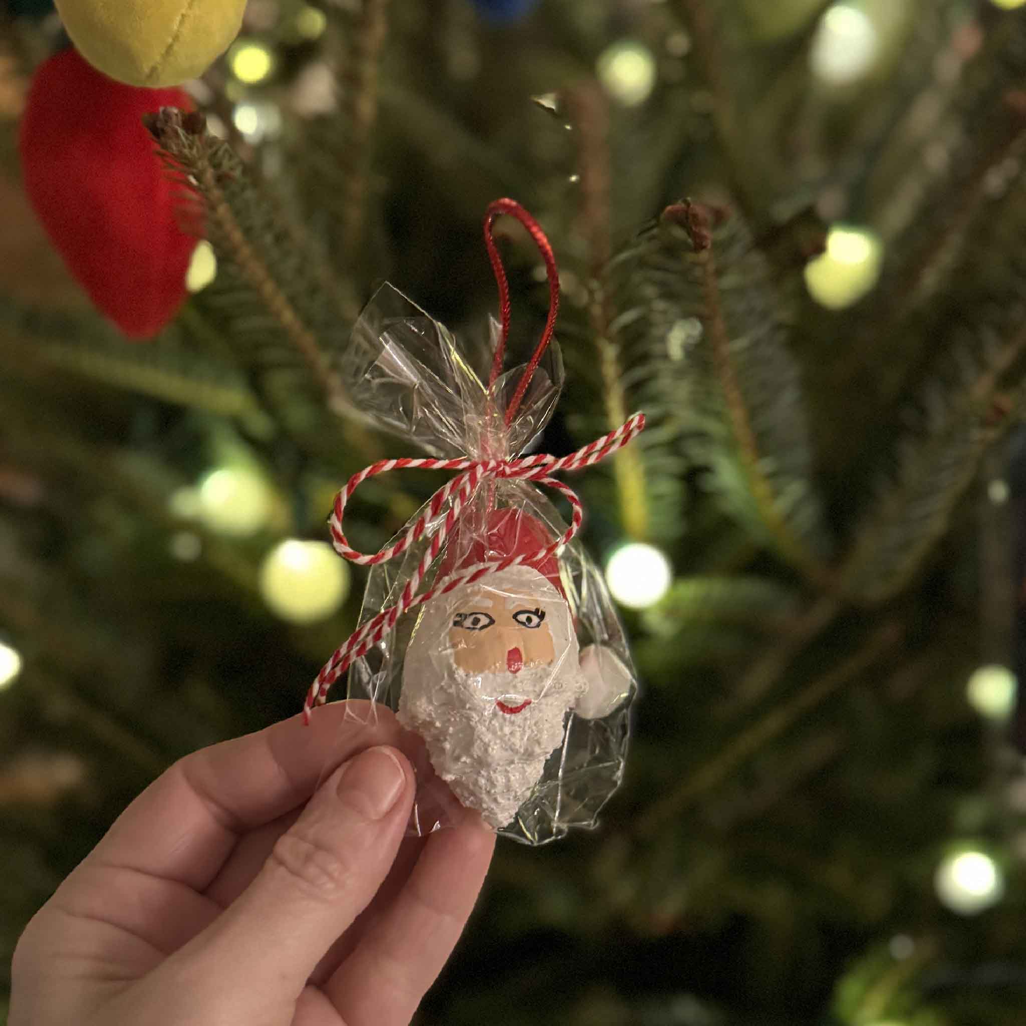 Hand-painted conch shell Santa ornament by Tootsie Watkins with red hat and textured white beard, bagged for gifting.