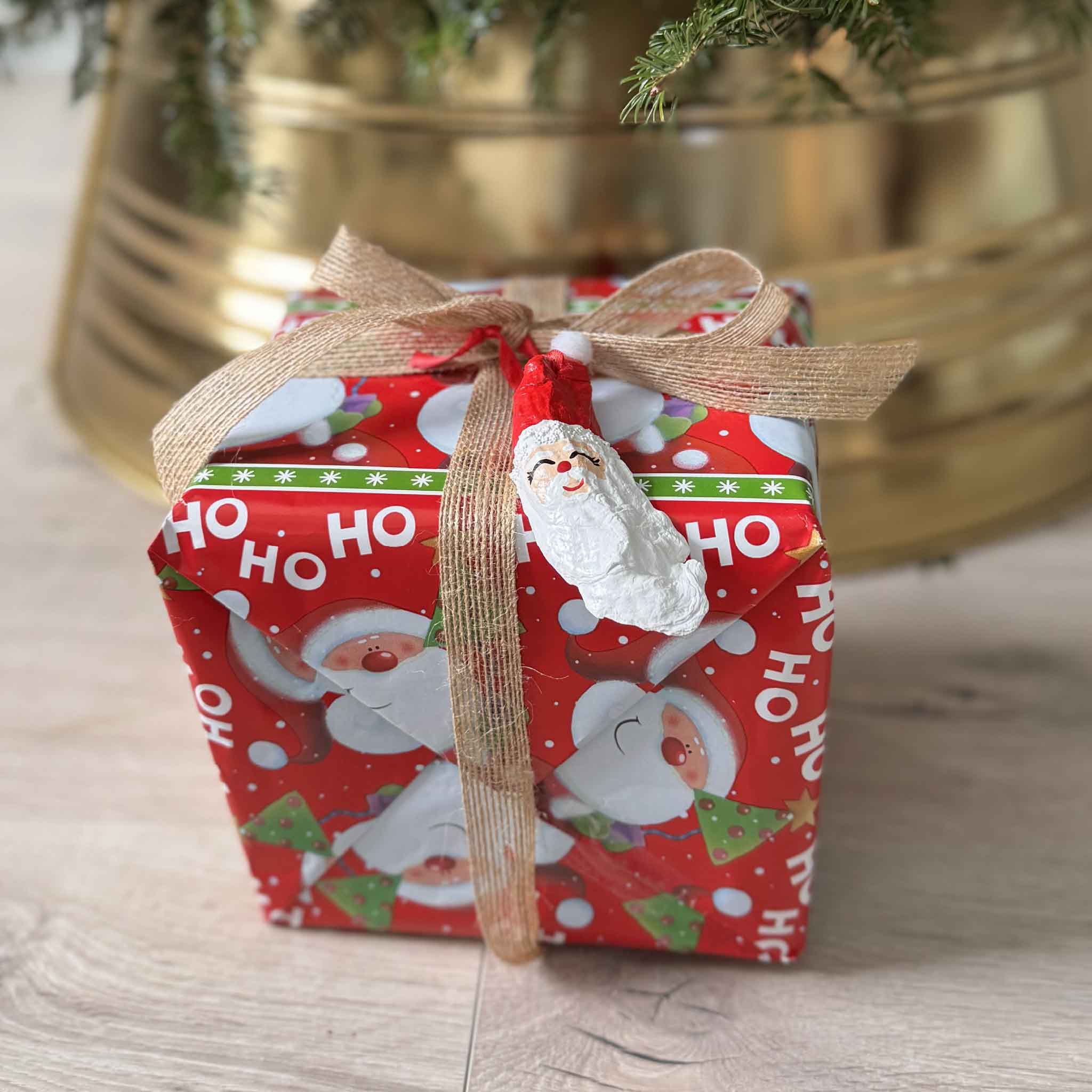 Hand-painted oyster shell Santa ornament with red hat and white beard, created by artist Tootsie Watkins. Shown a gift tag accessory at Gray Man Gallery.