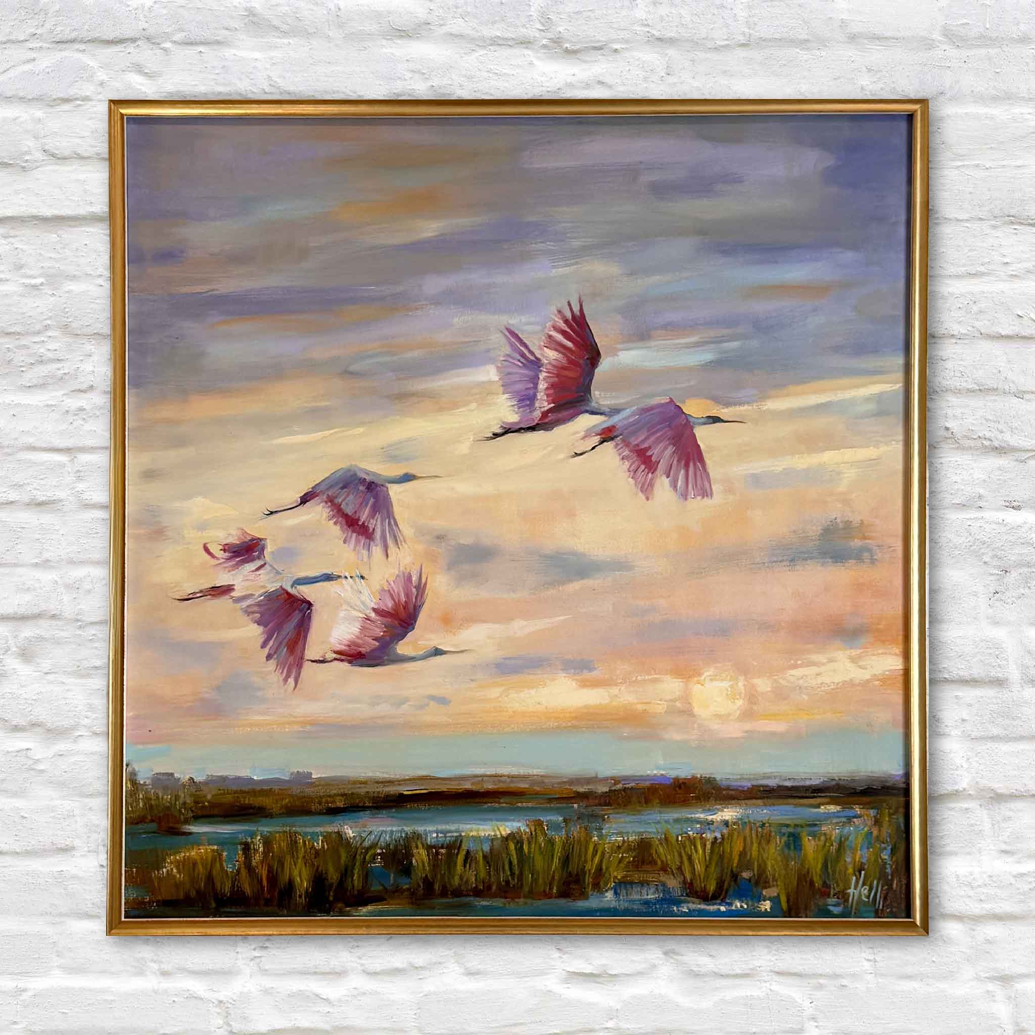 Twilight Ballet original painting by local artist Helli Luck featuring roseate spoonbills in flight over a Pawleys Island marsh at sunset, beautifully framed in Jeanne’s signature gold frame at Gray Man Gallery