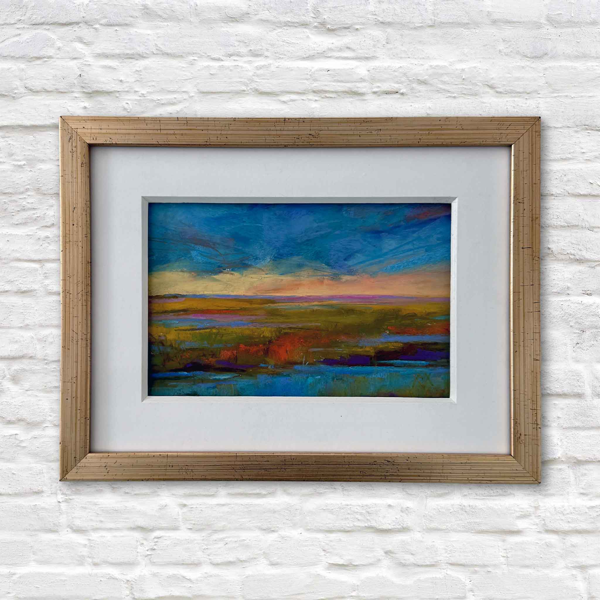 Original pastel painting “Evening Glow” by local Lowcountry artist Vida Miller, professionally matted and custom framed at Gray Man Gallery in Pawleys Island, South Carolina, featuring a colorful coastal landscape displayed on a white brick wall