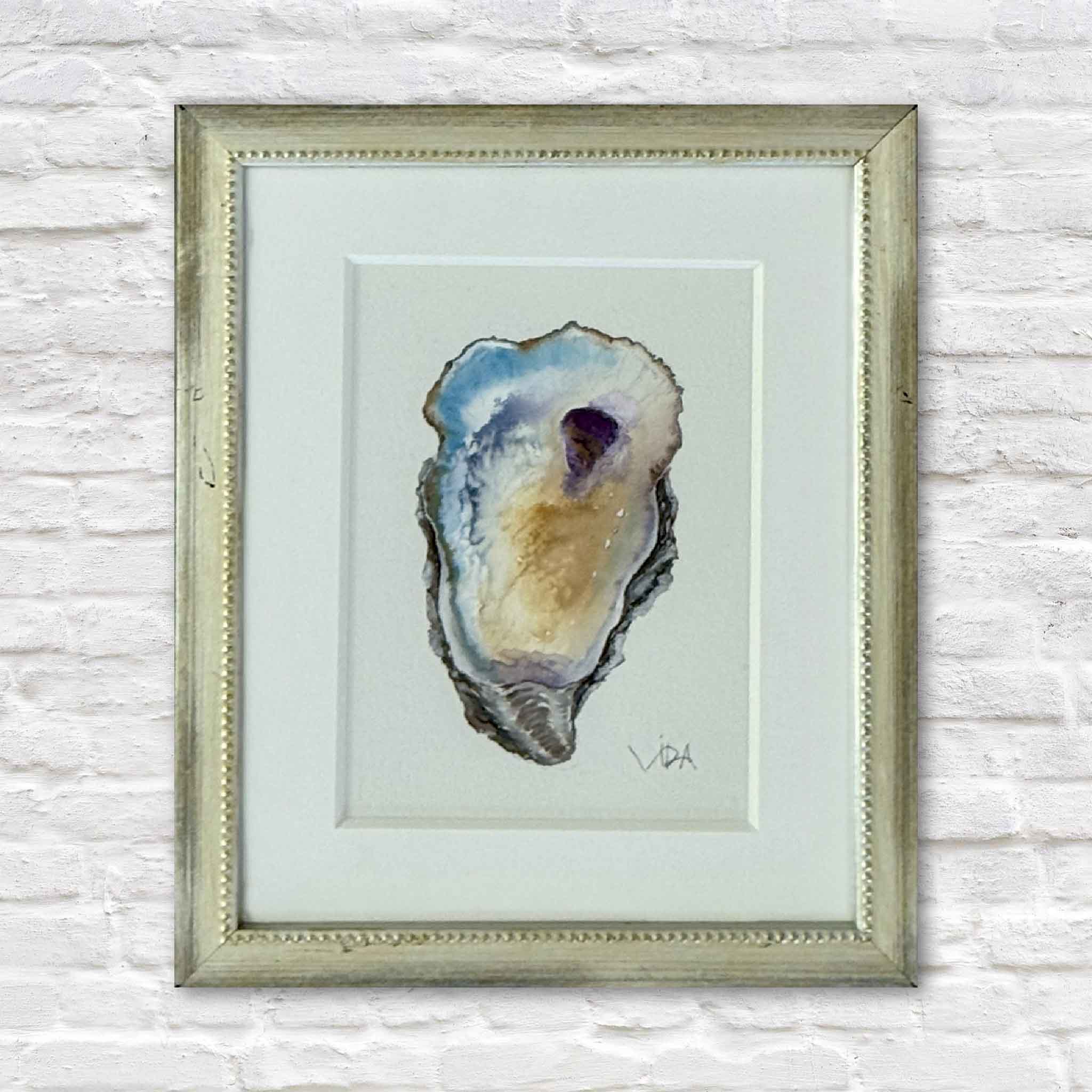 Pawleys Oyster V original watercolor by Pawleys Island artist Vida Miller, featuring a single Lowcountry oyster shell painted in soft blue, gold, lavender, gray and cream, professionally matted and custom framed in a softly antiqued metallic frame at Gray Man Gallery in Pawleys Island, South Carolina.