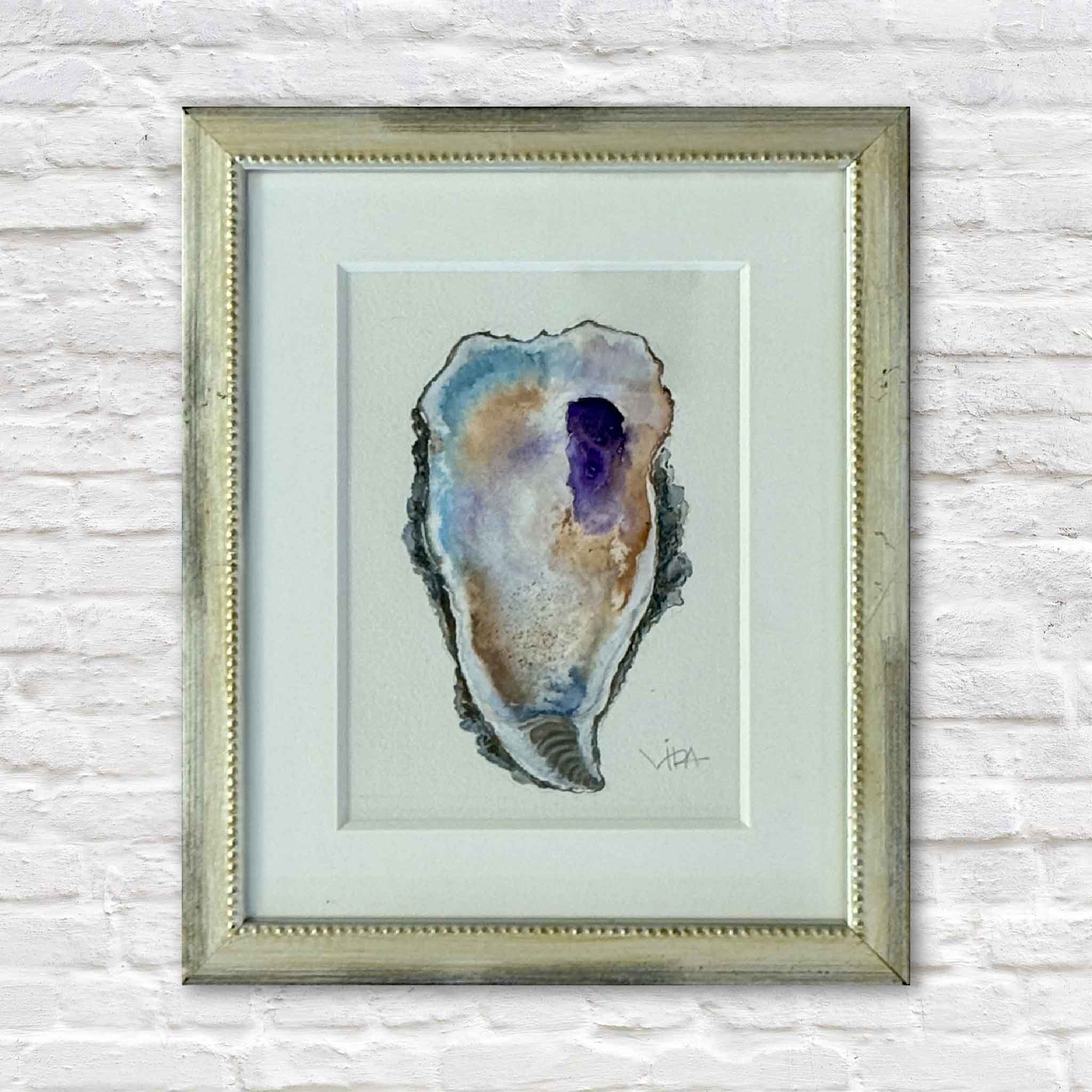 Gray Man Gallery team member holding Pawleys Oyster VIII, an original watercolor painting by Pawleys Island artist Vida Miller featuring a colorful Lowcountry oyster shell in blue, violet, lavender, ochre, cream, and gray, professionally matted and framed and shown inside Gray Man Gallery in Pawleys Island, South Carolina.