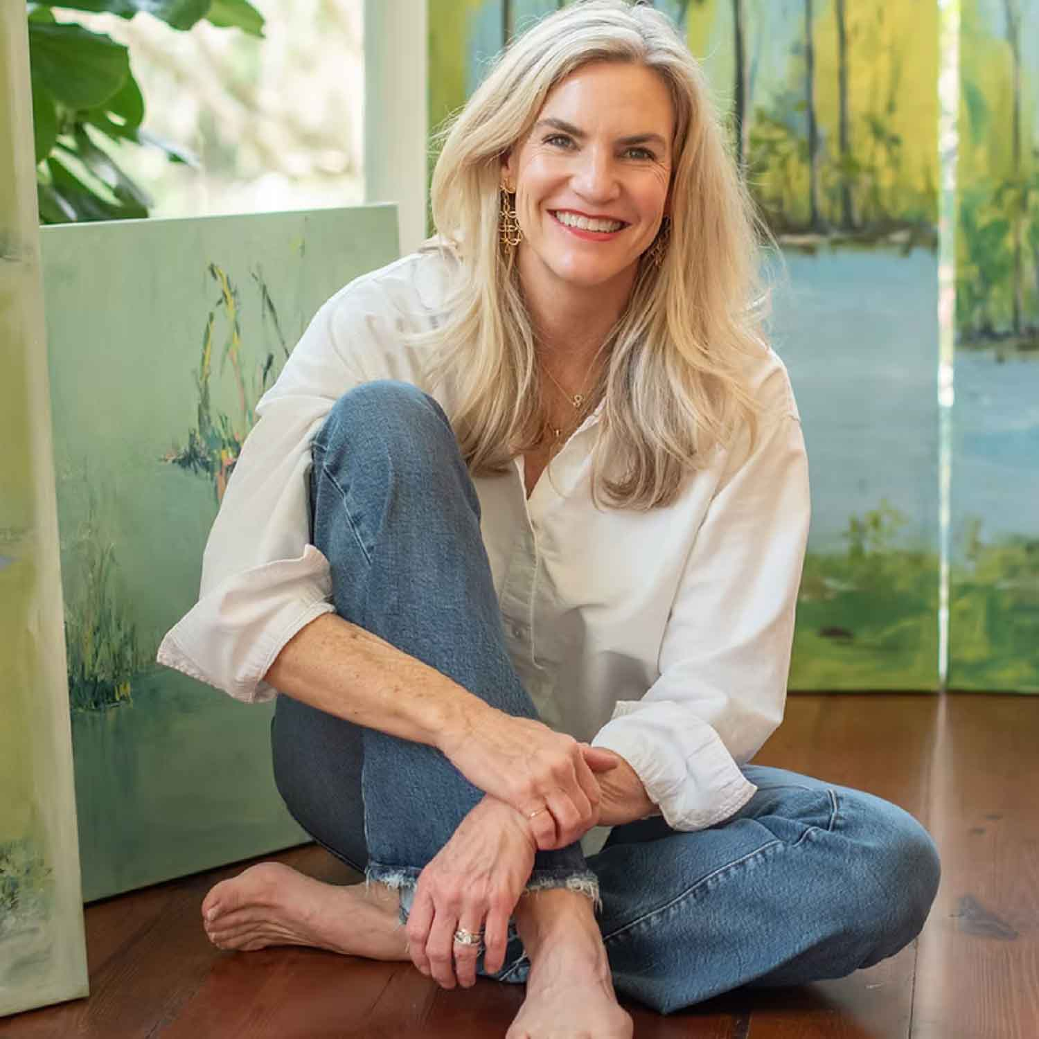 Braden Grafe sitting on the floor on front of her art.