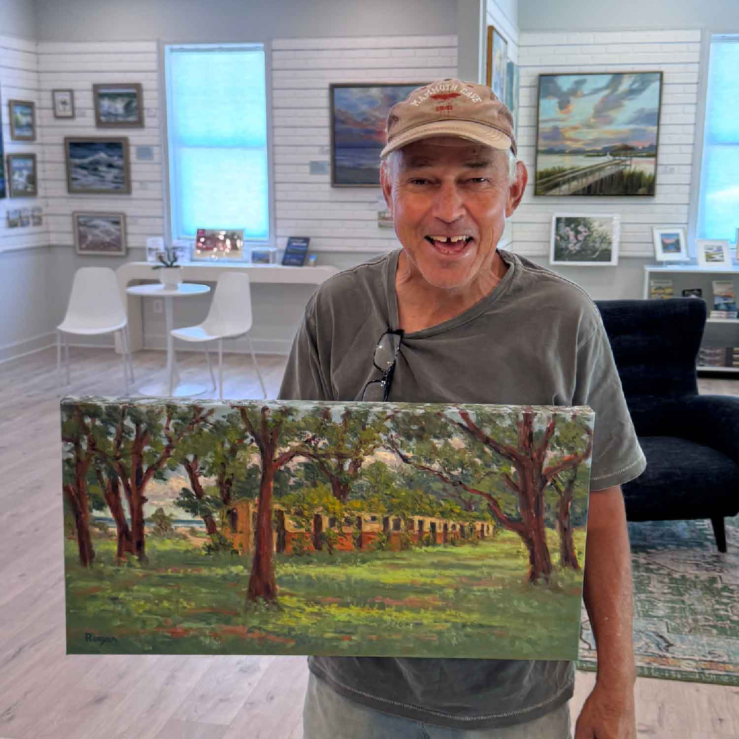Michael Rogan at Gray Man Gallery holding his painting of McKenzie Beach