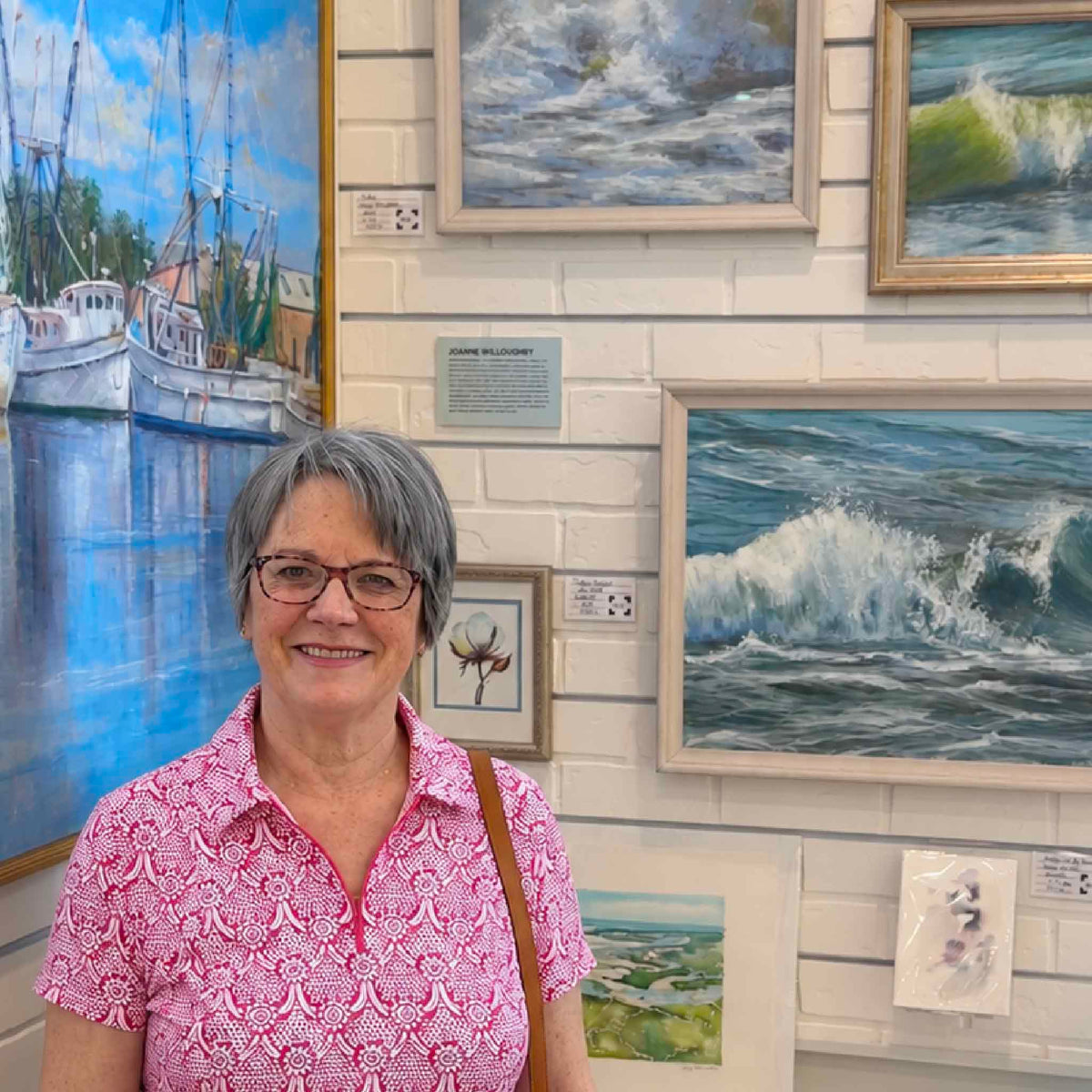 South Carolina pastel artist Joanne Willoughby inside Gray Man Gallery in Pawleys Island, surrounded by her original coastal paintings, ocean scenes and Lowcountry artwork on display in the gallery