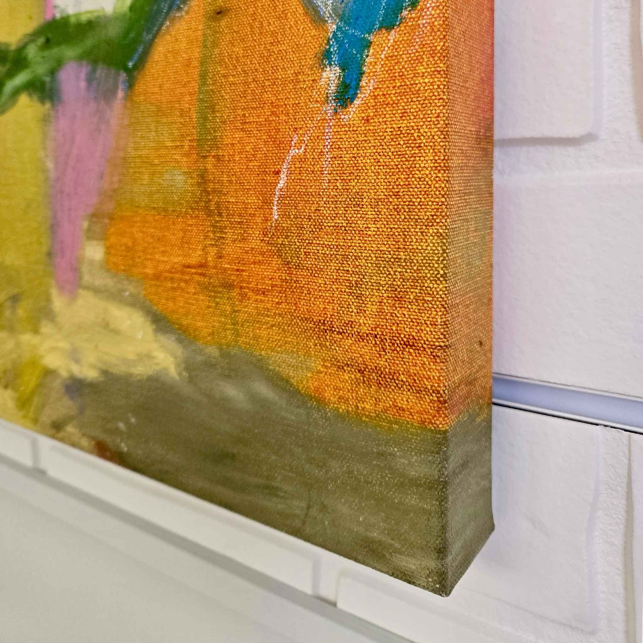 Close-up of a textured painting with orange, blue, and green colors on a white wall.
