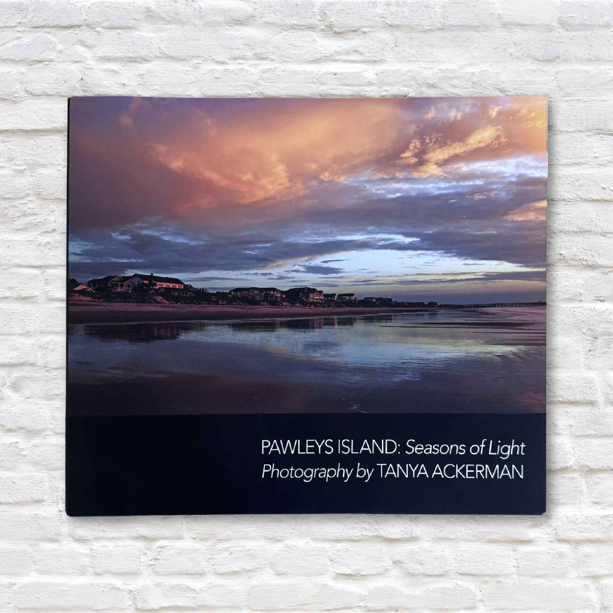 Front cover of Pawleys Island: Seasons of Light by Tanya Ackerman, Beach Cover Edition, showing a vivid sunset over Pawleys Island with homes and shoreline reflected in the water.