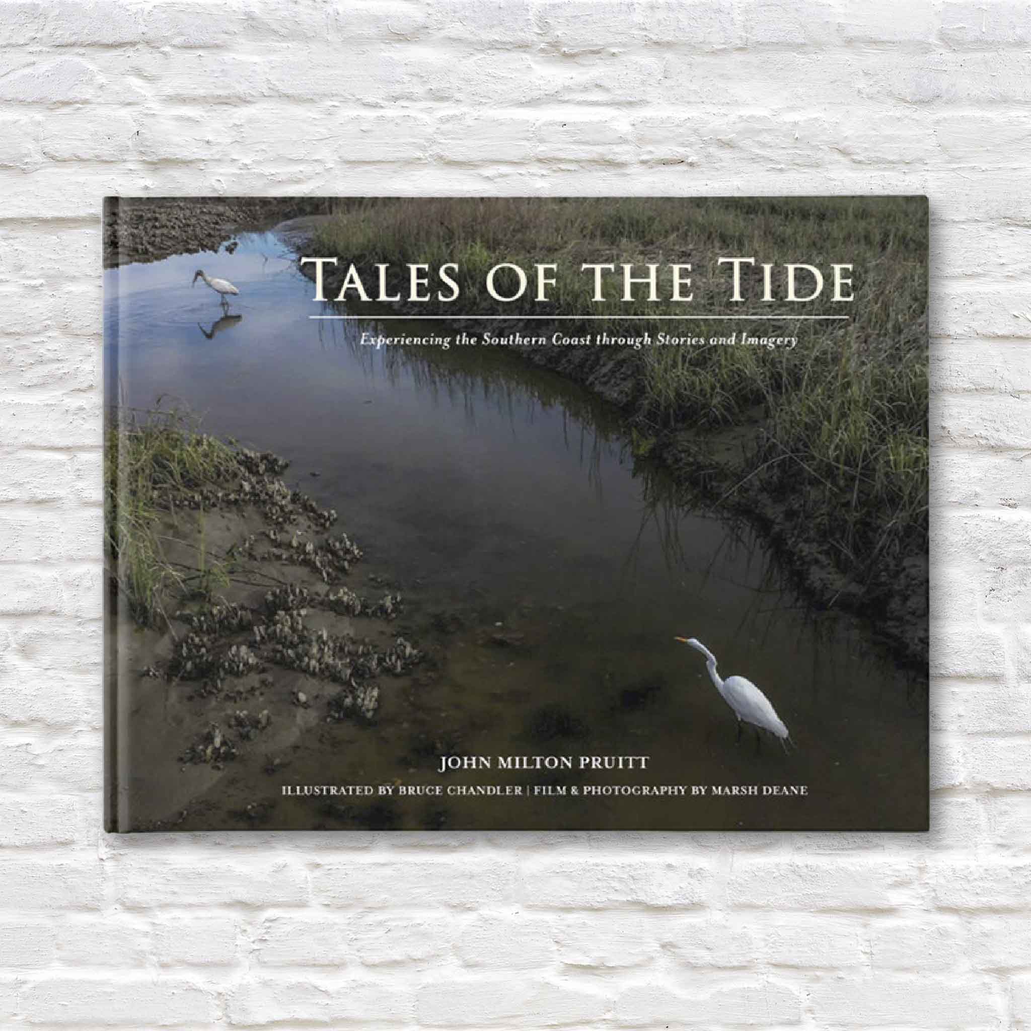  the book 'Tales of the Tide' by John Milton Pruitt, featuring a coastal marsh scene with two white egrets reflected in the still water. The subtitle reads 'Experiencing the Southern Coast through Stories and Imagery.' Illustrations by Bruce Chandler and photography by Marsh Deane