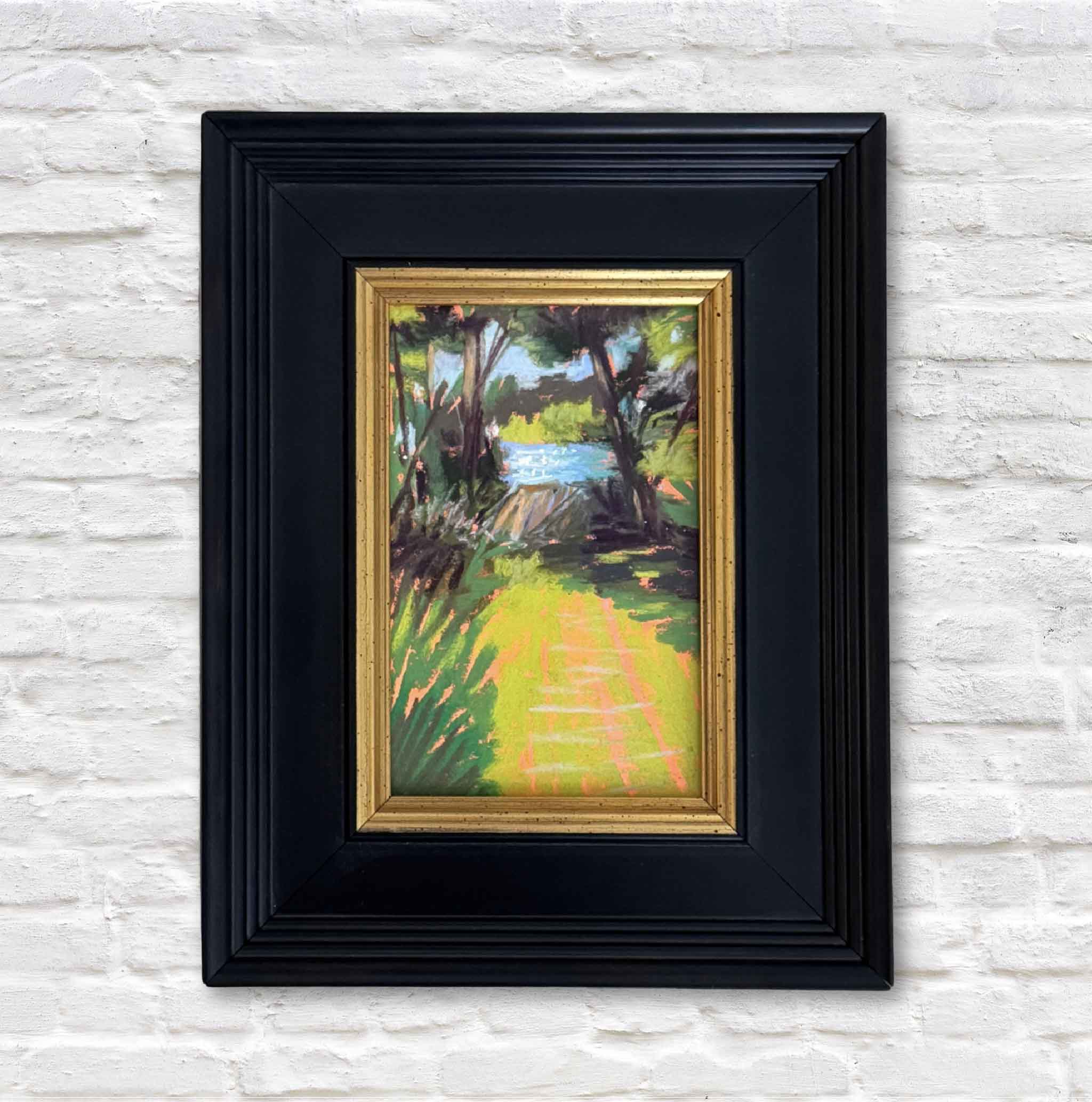 Framed painting of a landscape with a black frame on a textured white wall.