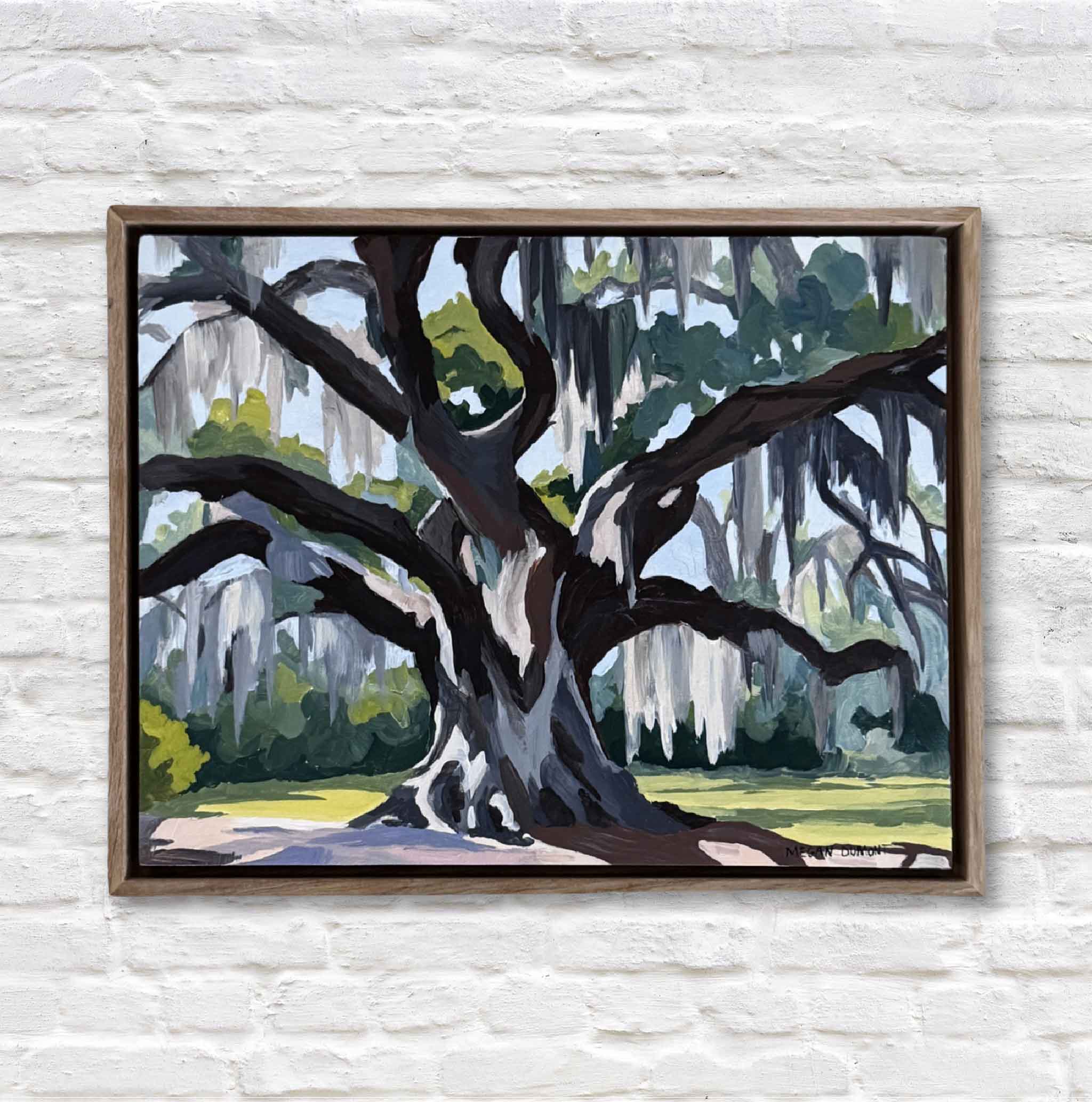 Framed painting of a large oak tree with Spanish moss on a white brick wall.